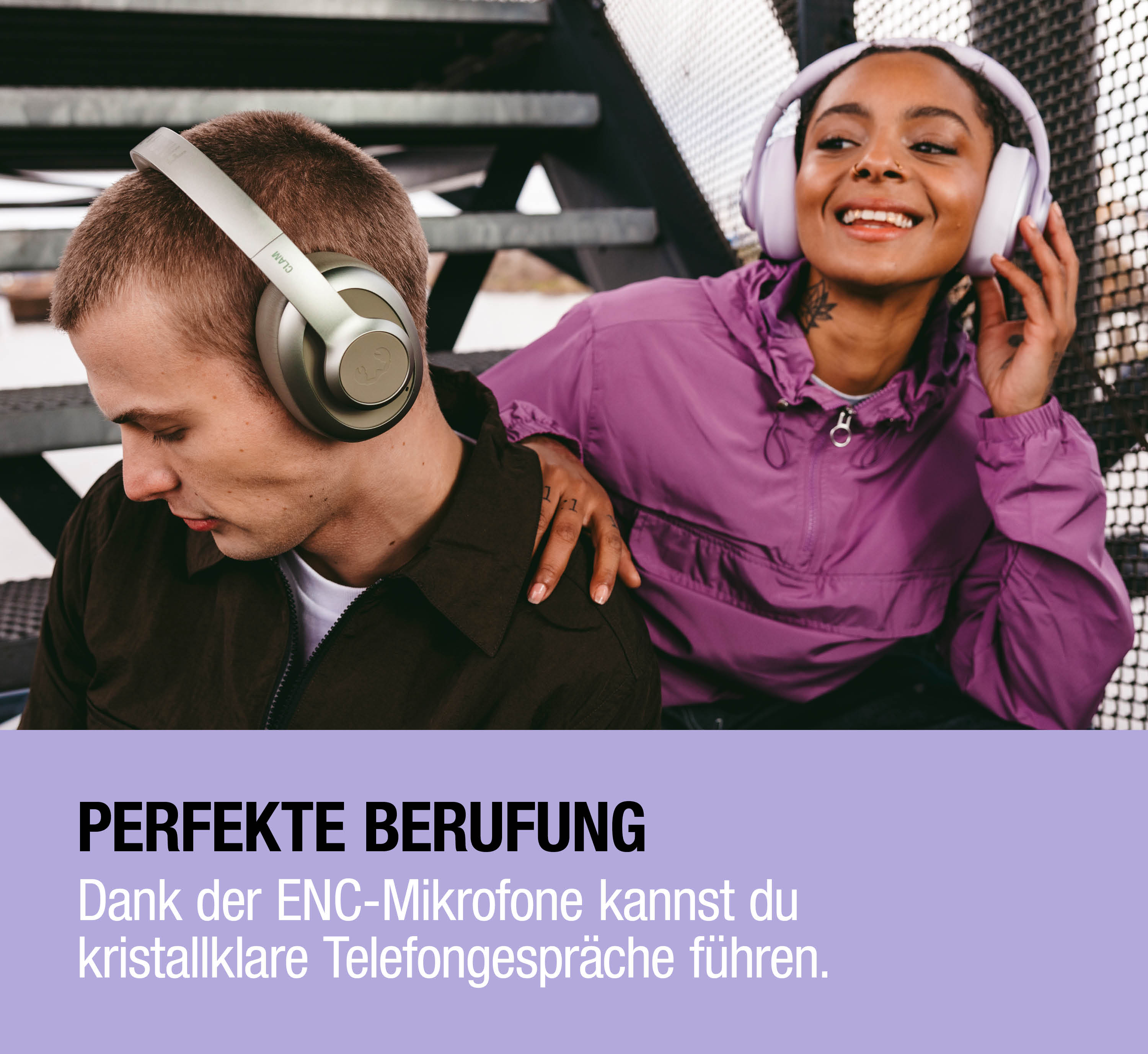 Mann und Frau mit Kopfhörern sitzen auf einer Treppe, Frau legt Hand auf Mann.