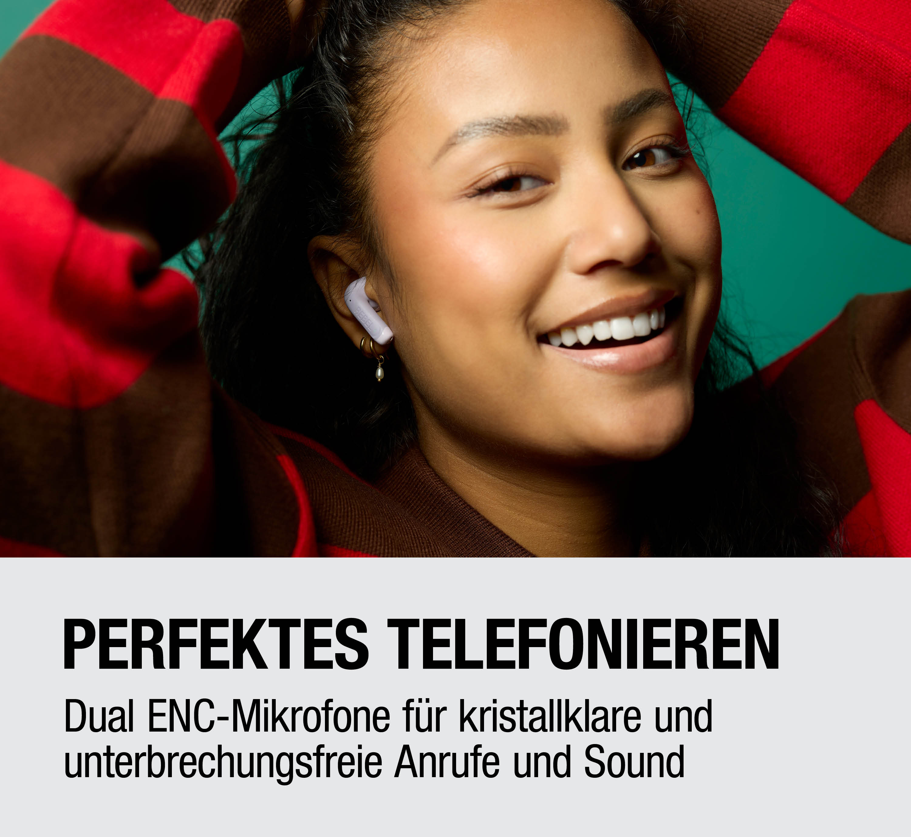 Frau mit Kopfhörern lächelt. Rotes und braunes gestreiftes Oberteil.