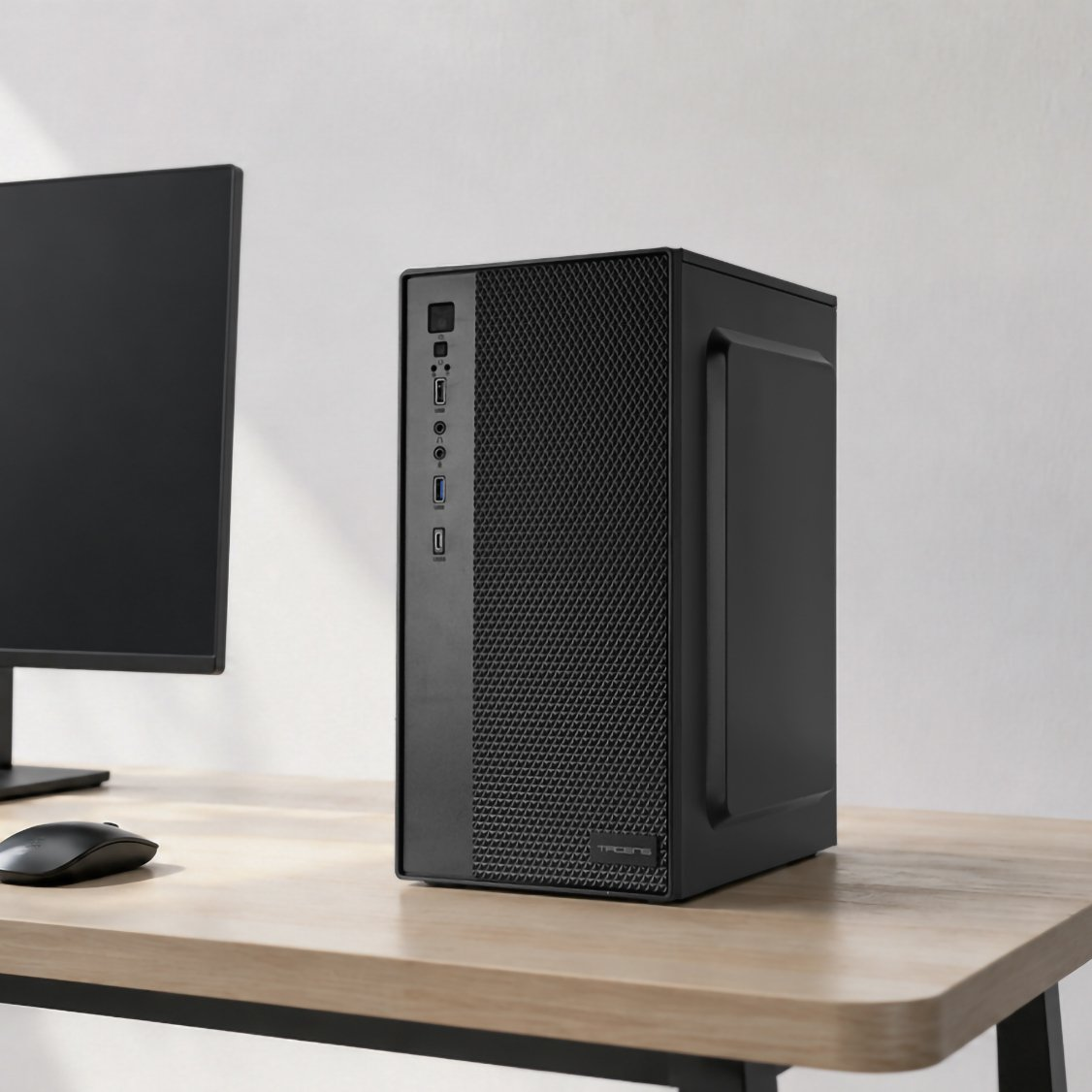 Una torre de PC negra se sienta junto a un monitor y un ratón en un escritorio de madera.