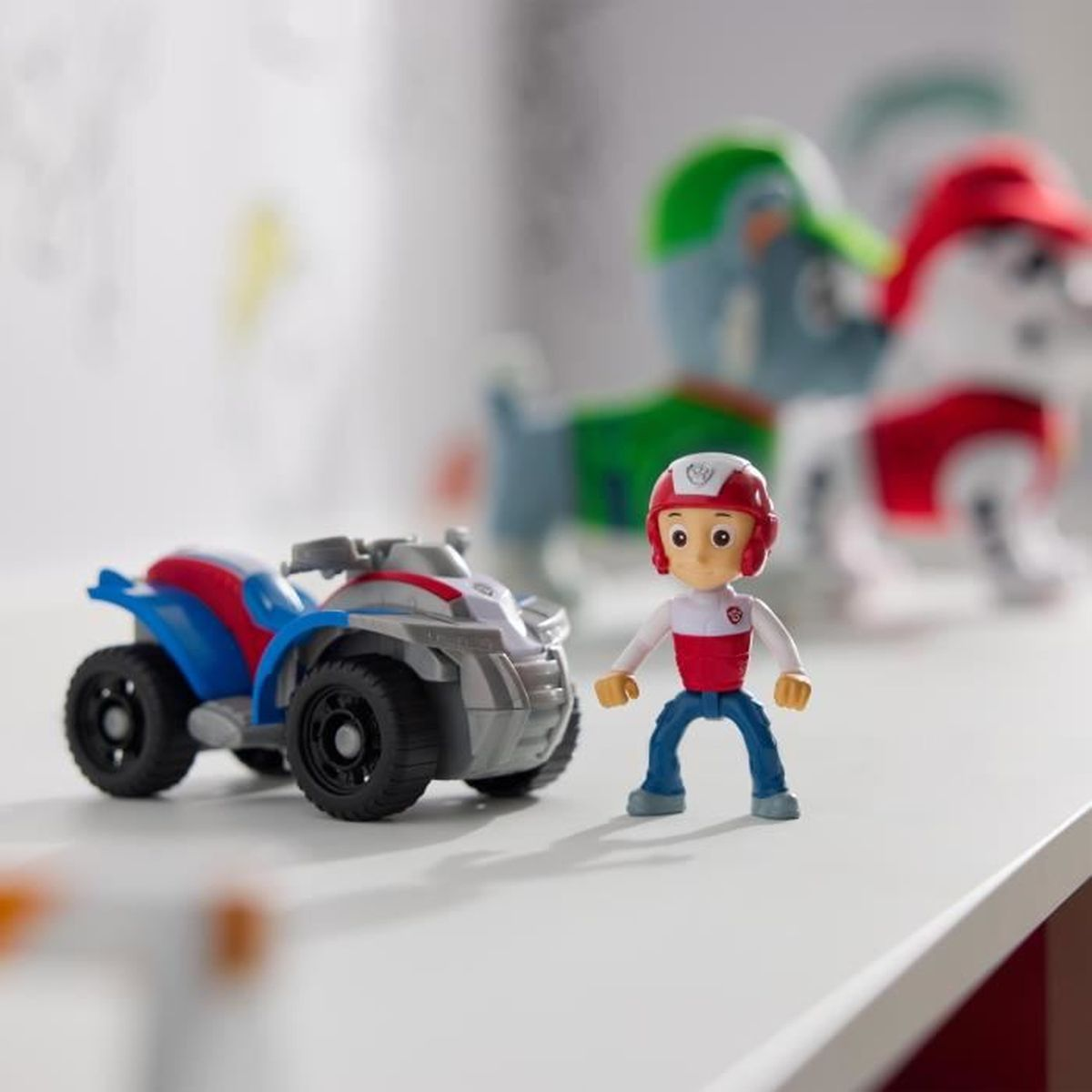 Un quad de juguete y una figura en un estante. Dos figuras de perros al fondo.