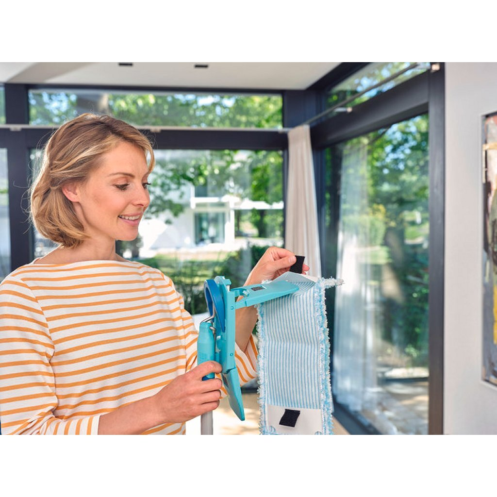 Donna in maglia a righe attacca testa di mocio blu a strumento per pulire.