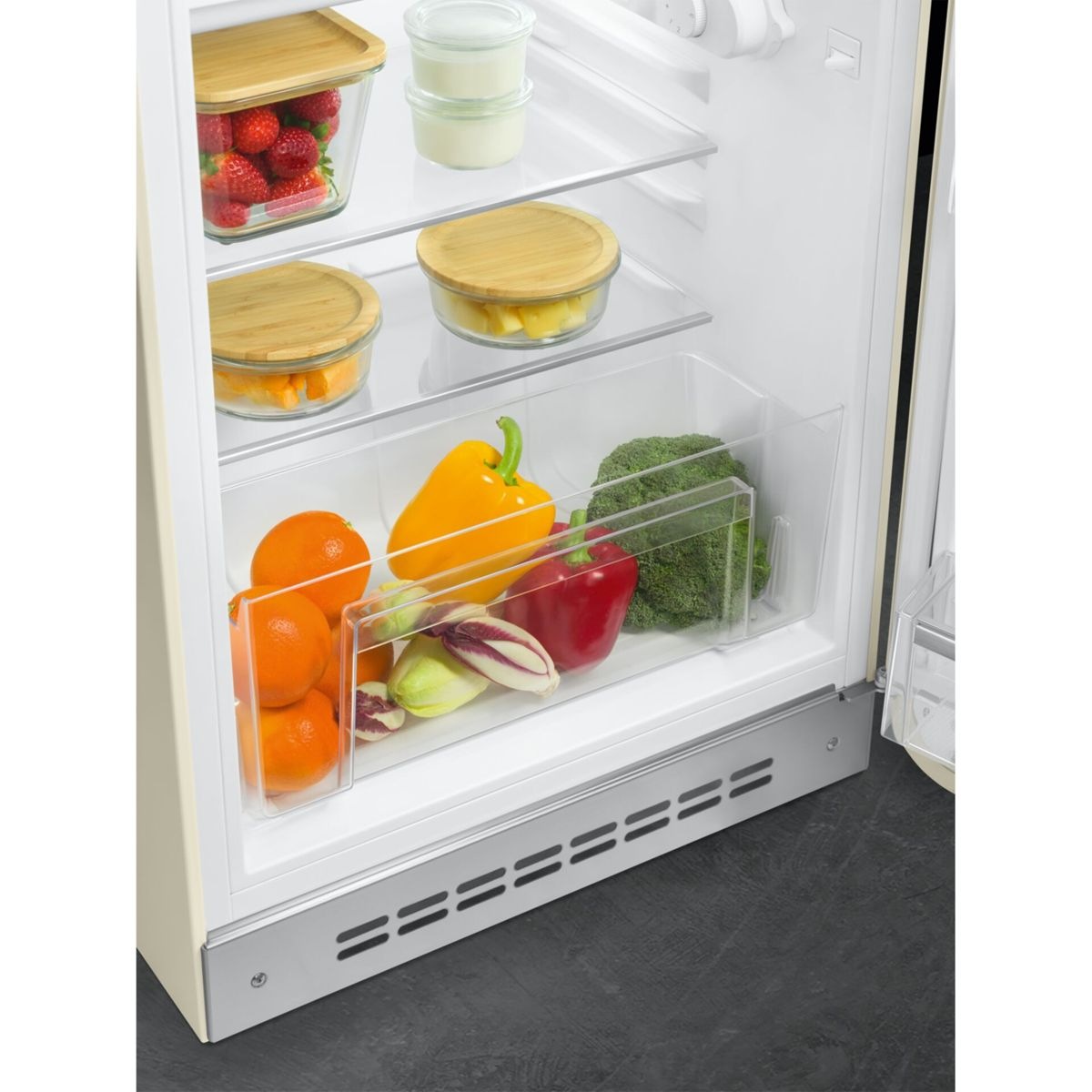 Cajón de refrigerador con naranjas, pimientos, brócoli y radicchio. Arriba hay bayas y yogur.