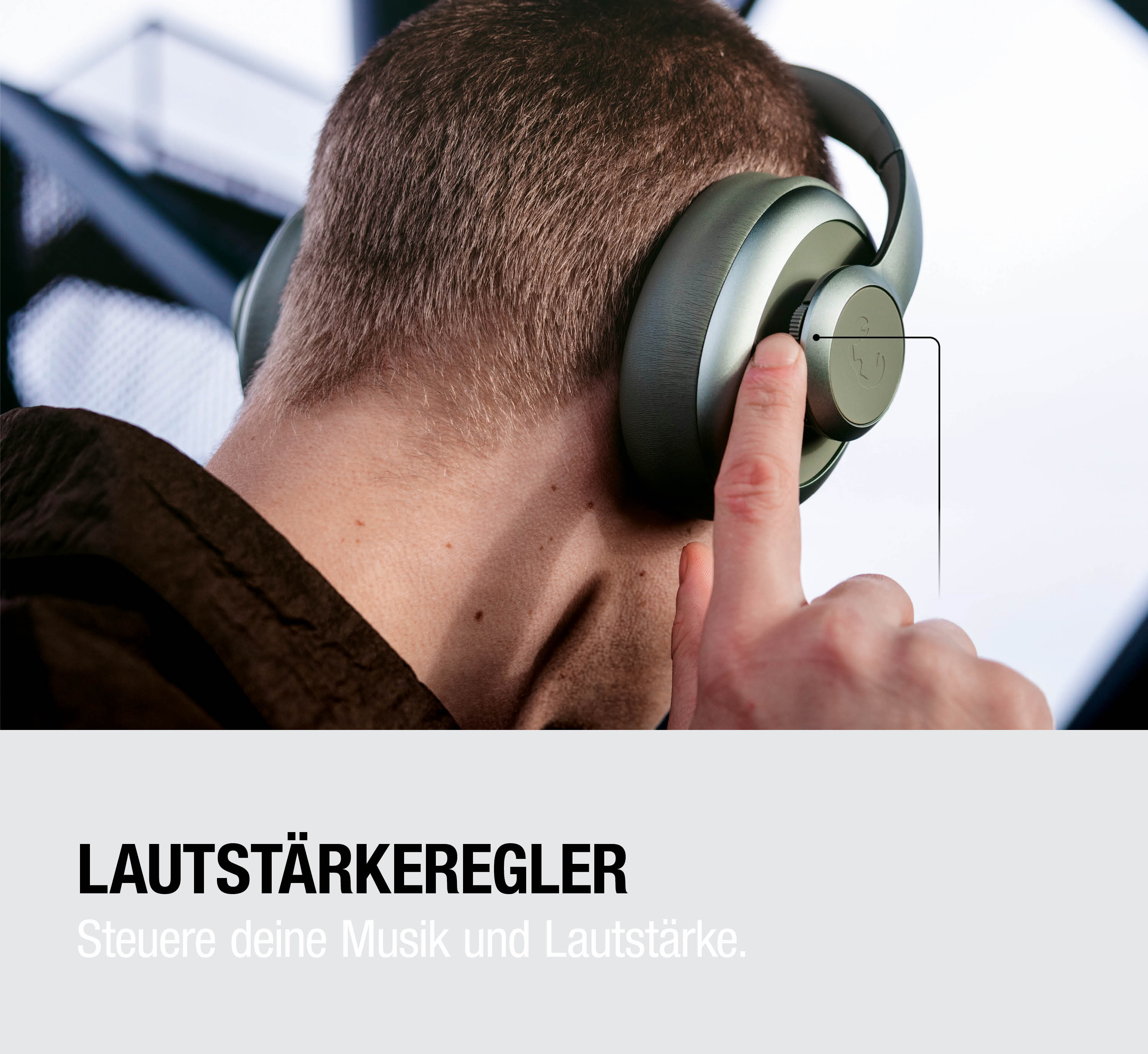 Nahaufnahme einer Person mit großen Kopfhörern, Finger stellt Lautstärkeregler ein.