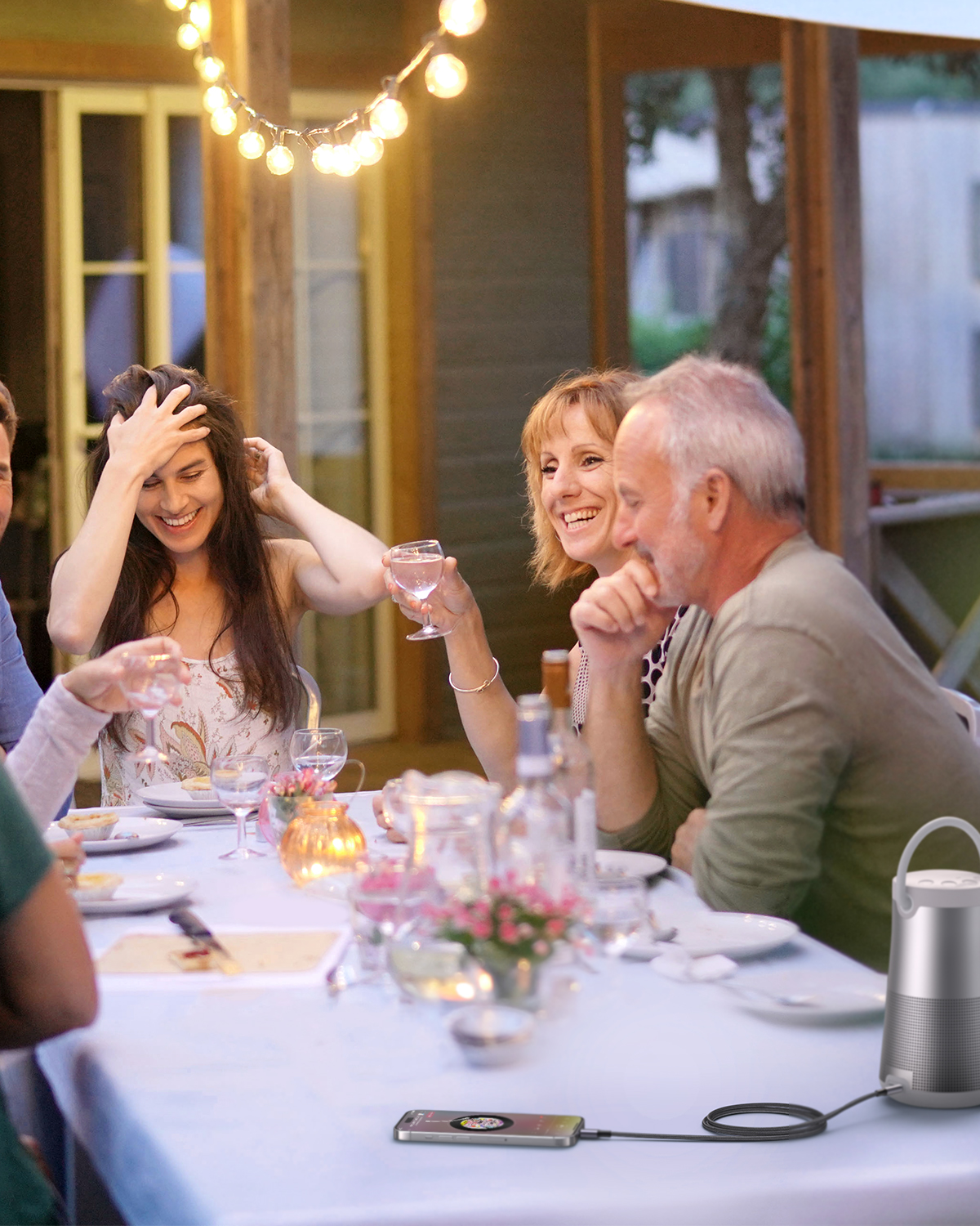People celebrating outdoors with candles and string lights.