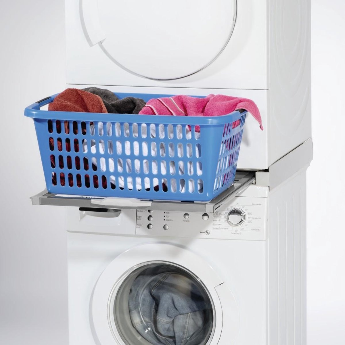 Blauer Wäschekorb mit Kleidung auf einer Waschmaschine, darunter ein Trockner.