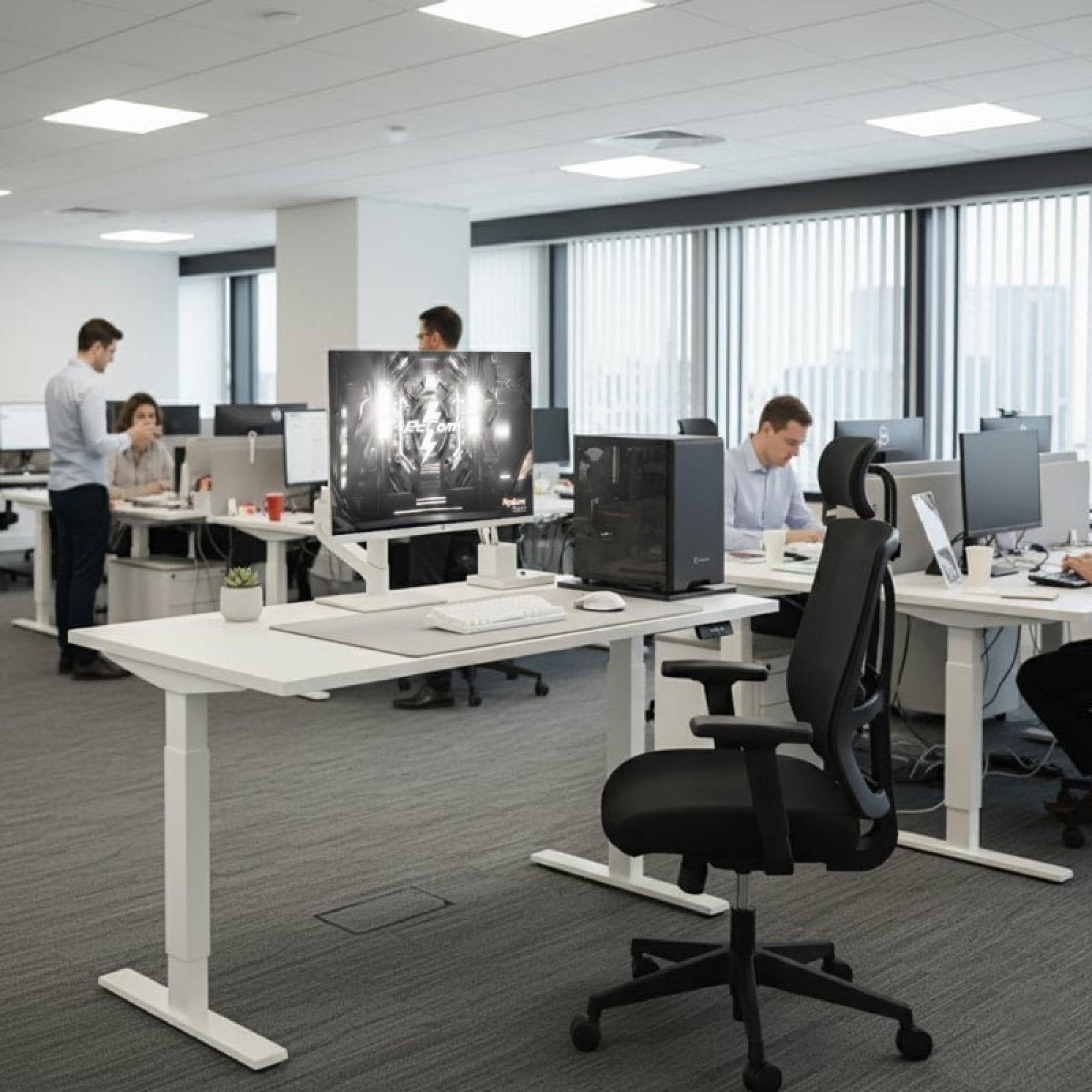 Ufficio moderno con persone che lavorano a scrivanie, computer e sedie.