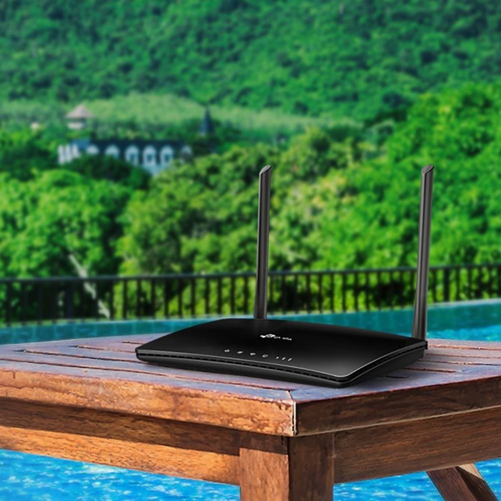 Een zwarte wifi-router met twee antennes staat op een houten tafel.