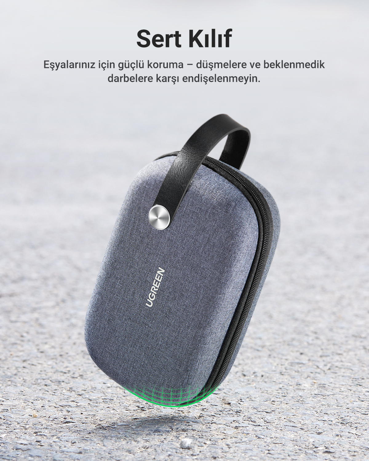 Graue UGREEN Tasche mit schwarzem Griff, liegt auf Beton.
