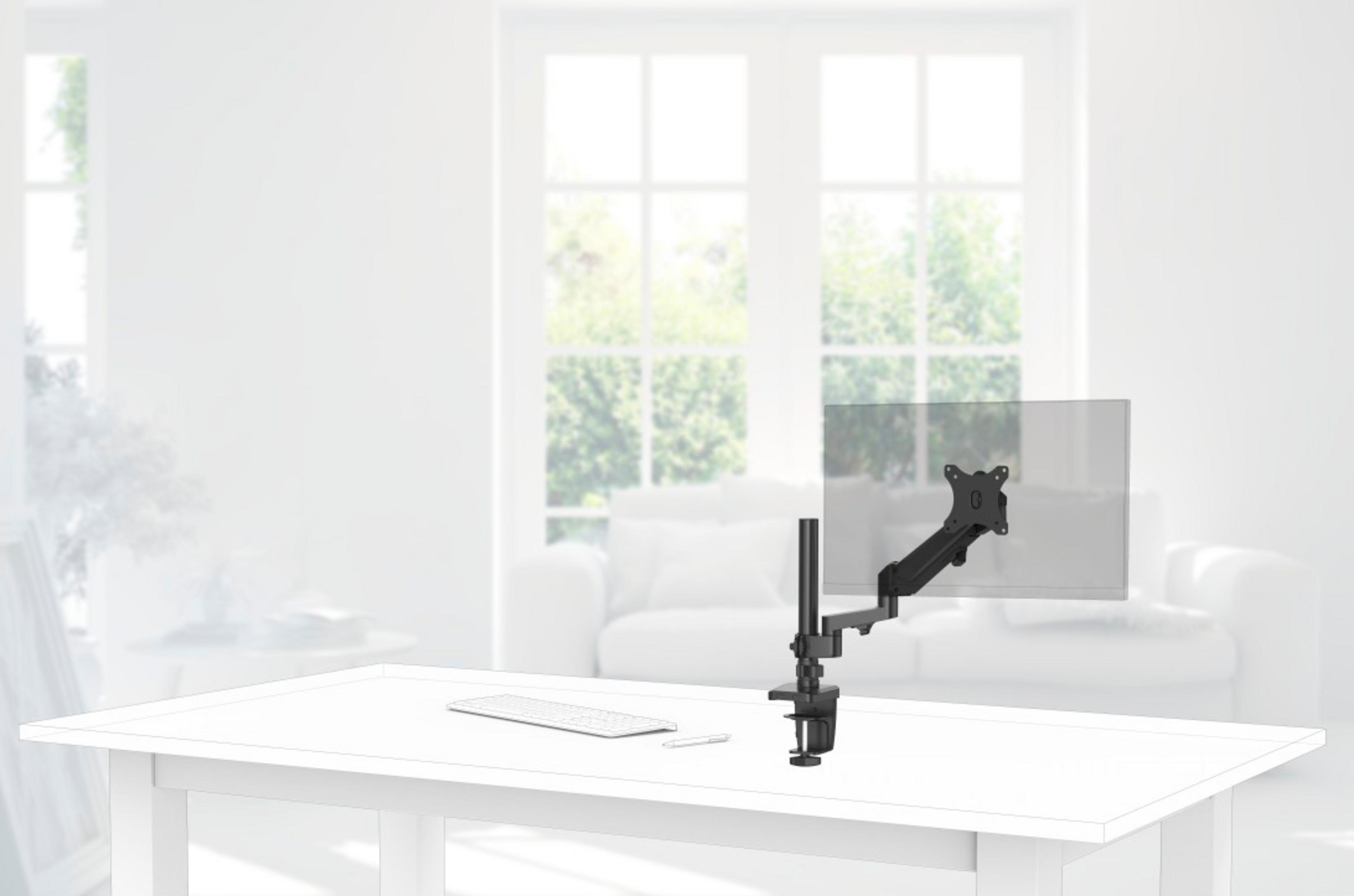 Ein Monitorarm klemmt an einem Schreibtisch mit Tastatur und Stift. Im Hintergrund sind Fenster.