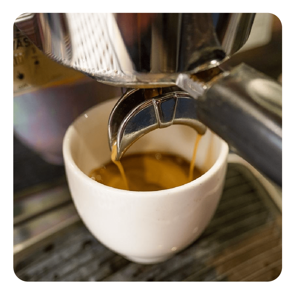Eine Espressomaschine brüht Kaffee in eine weiße Tasse.