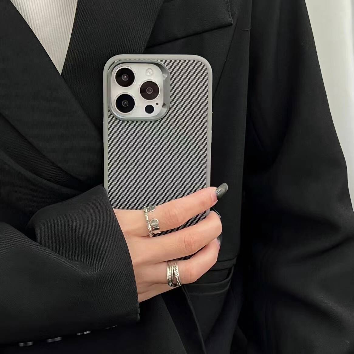 Yüzüklü bir el, damalı kılıflı bir telefon tutuyor.