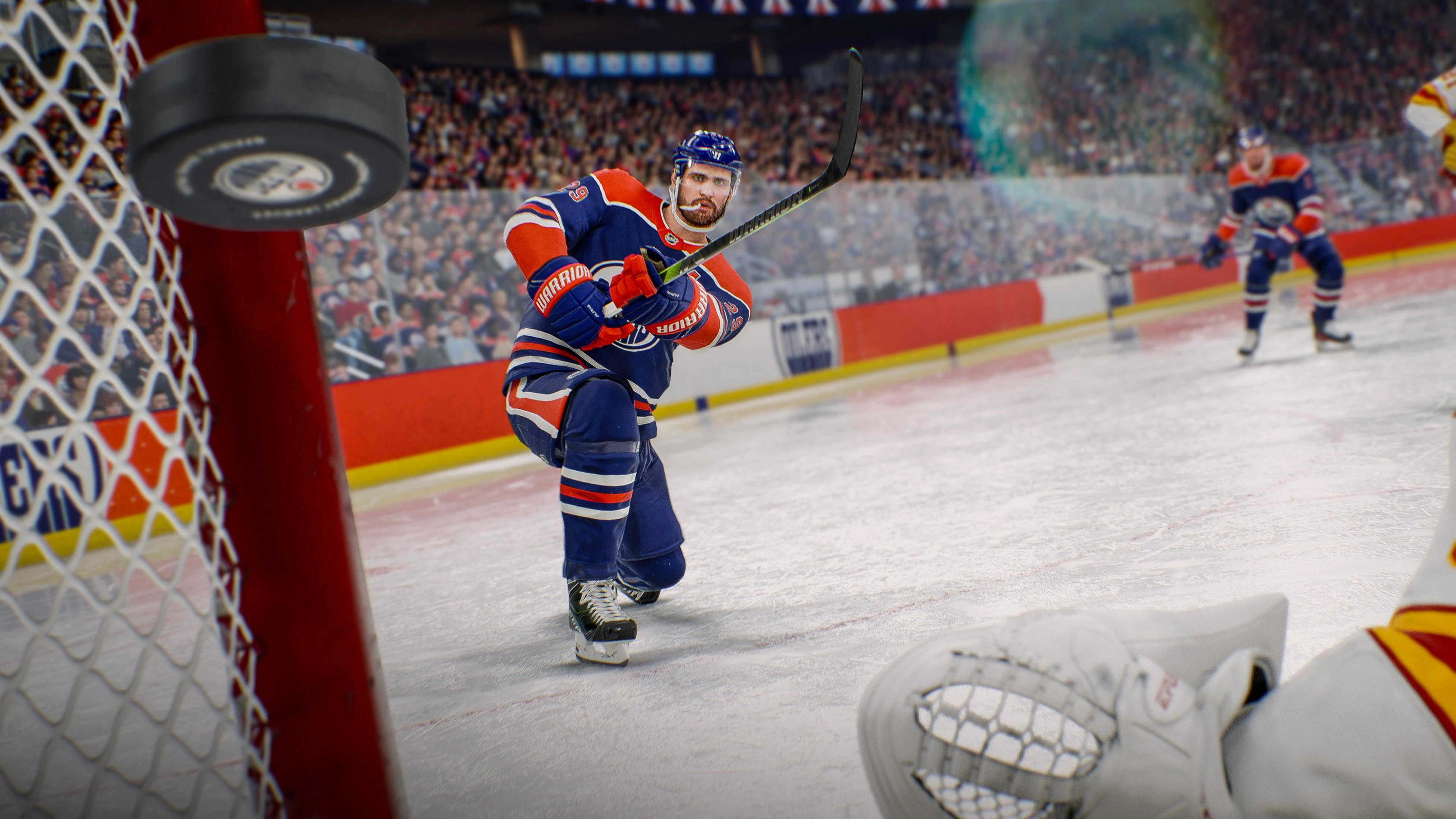 Ein Eishockeyspieler im blauen Trikot schießt den Puck aufs Tor, während ein Torwart pariert.