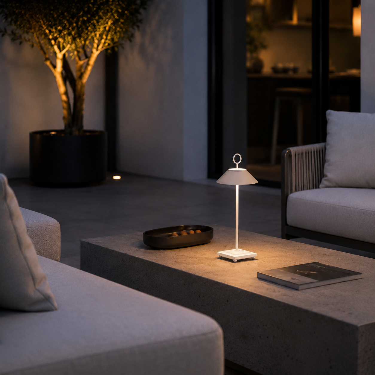 Eine weiße Lampe beleuchtet einen Couchtisch mit einer Schale und einem Buch.