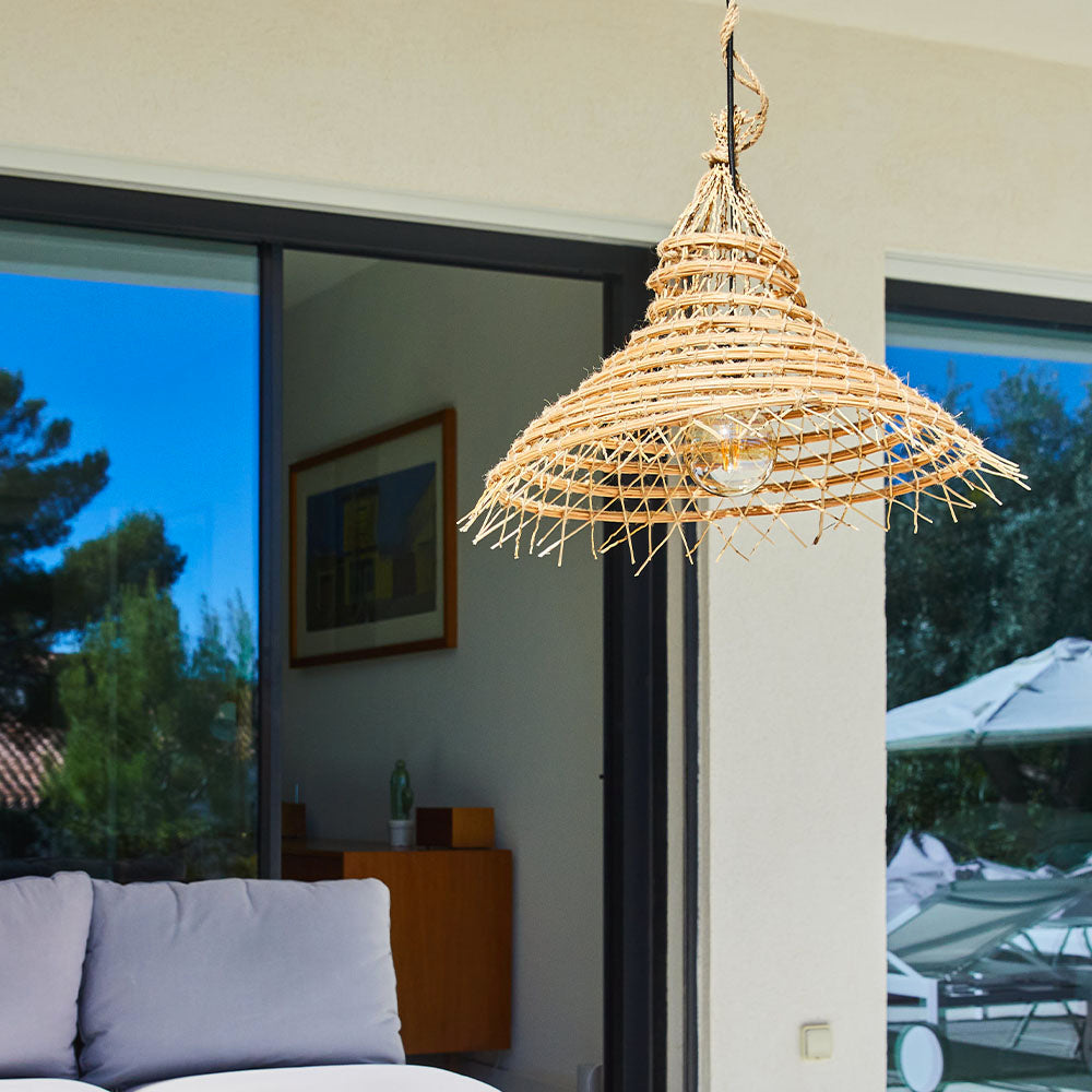 Eine hängende Lampe aus Weidengeflecht über einem Sofa im Freien.