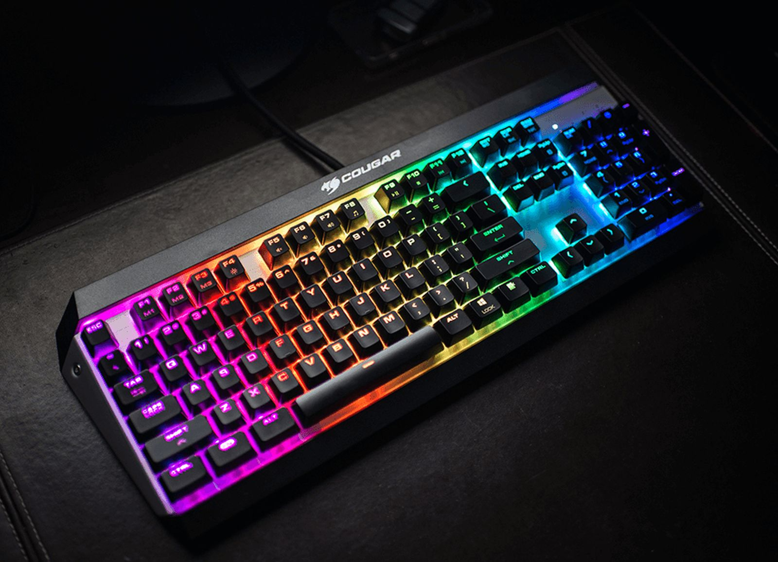 Eine schwarze Cougar-Tastatur mit lebendiger RGB-Beleuchtung, die Tasten wie ESC, F1-F10 und Buchstaben zeigt.