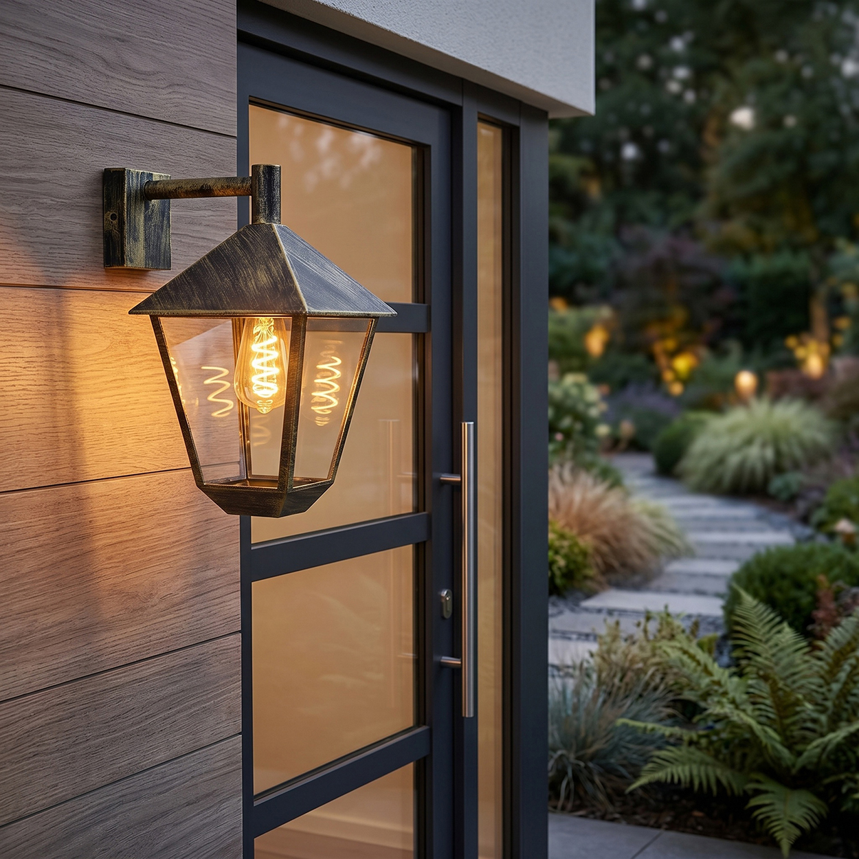 Eine Wandlaterne beleuchtet die Holzwand und die Glastür. Ein Gartenweg führt in die Ferne.