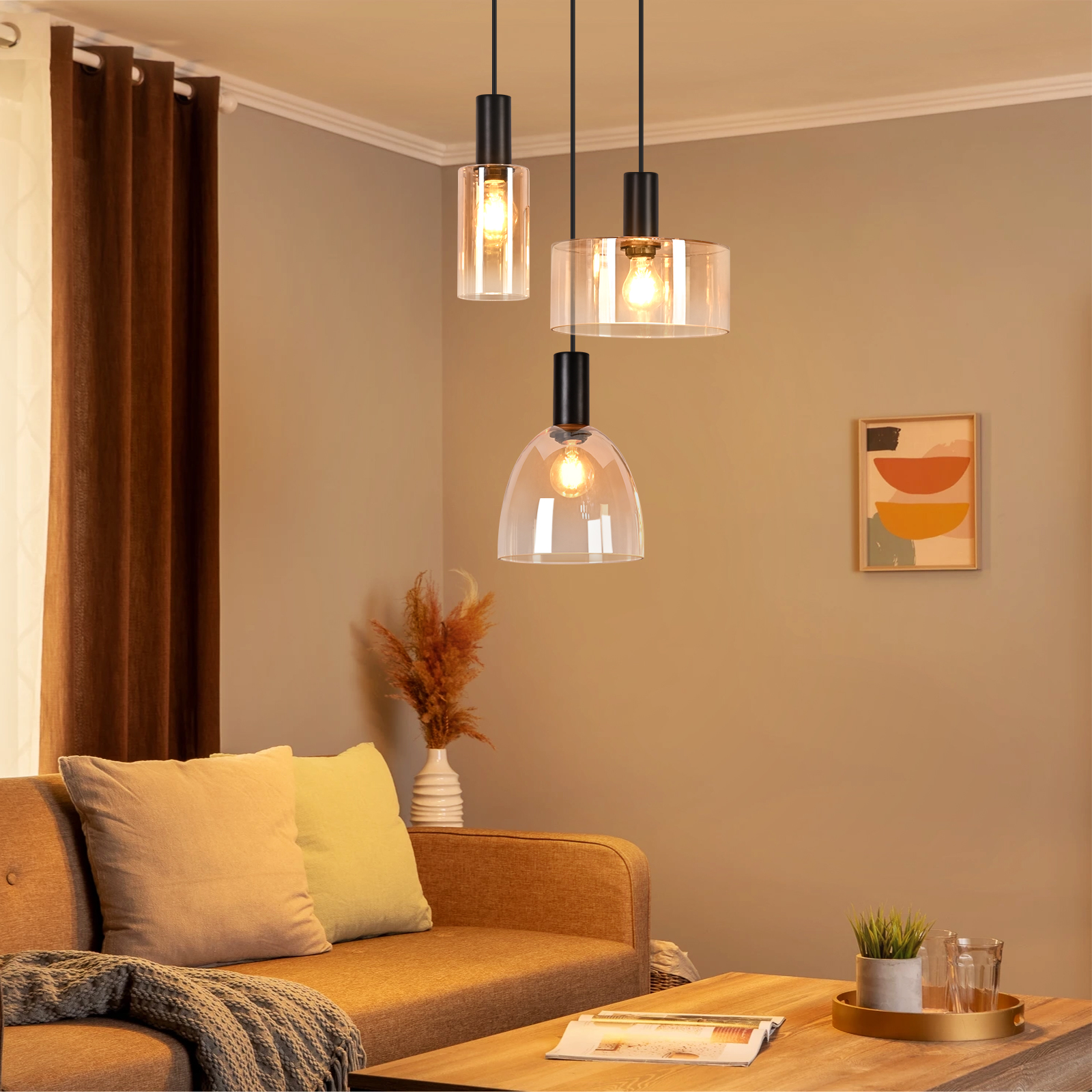 Drei Hängeleuchten über einem Sofa mit Kissen und Decke.