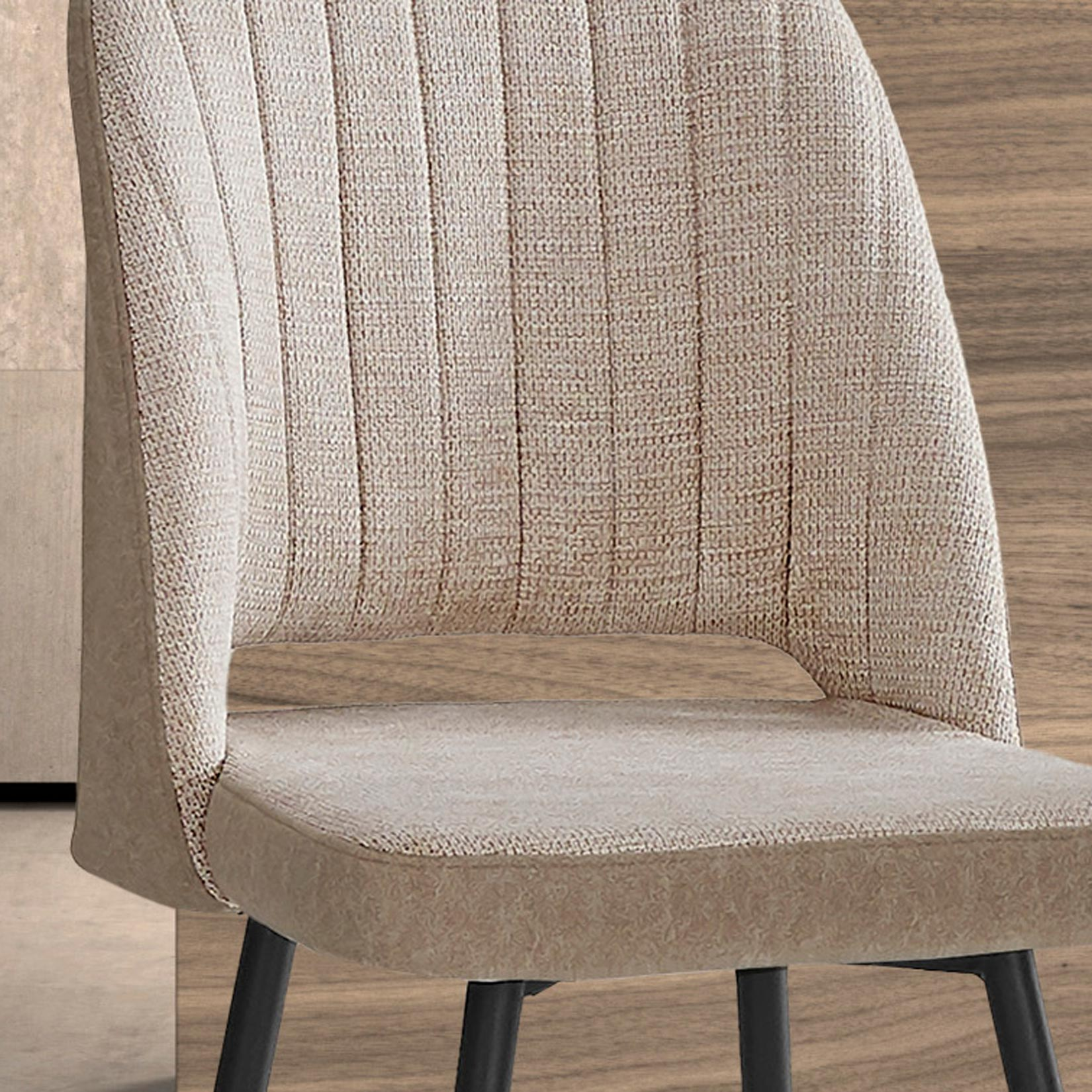 Una silla beige con costuras verticales y patas negras, sobre un suelo de madera.
