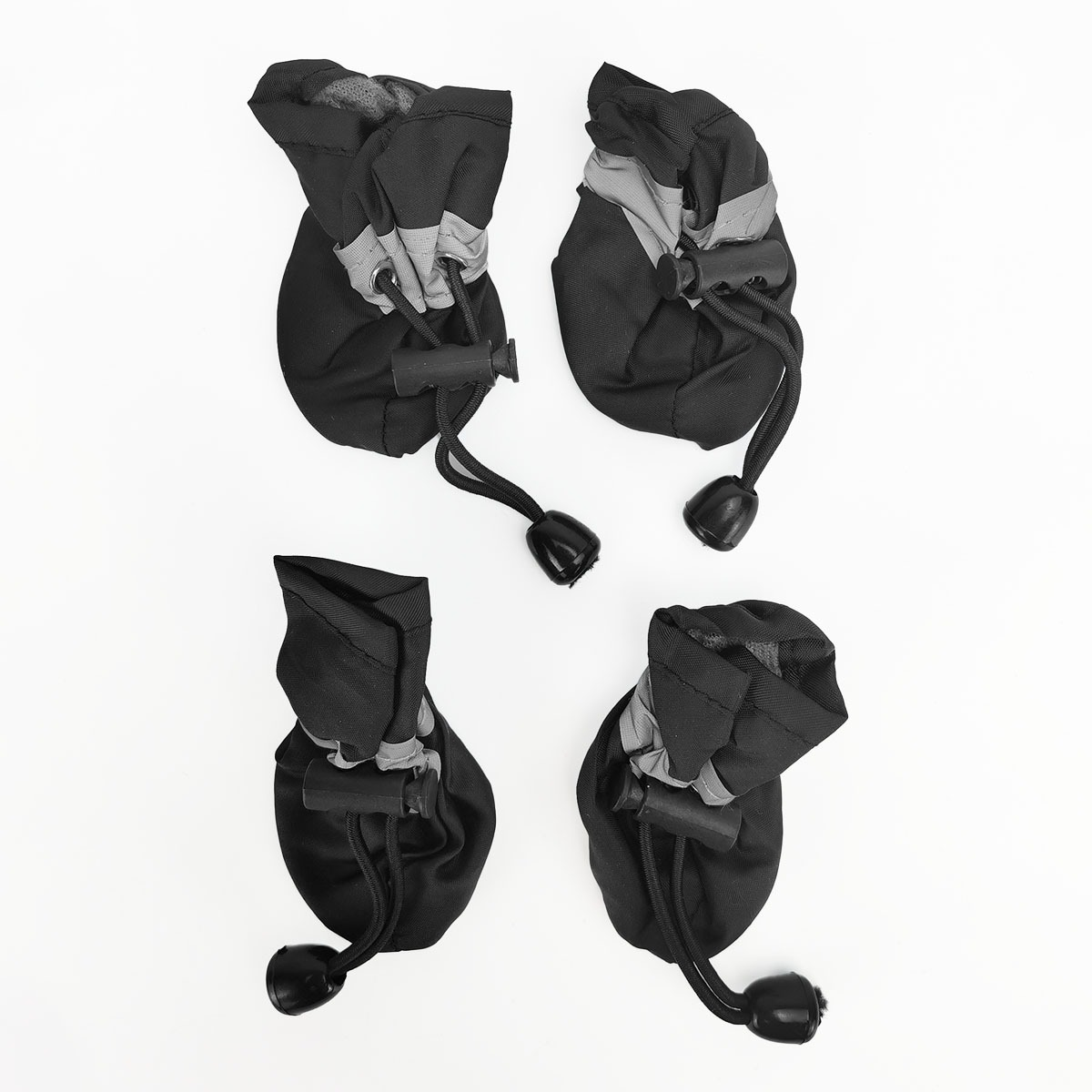 Vier schwarze Hundeschuhe mit reflektierenden Streifen und Kordelzügen.