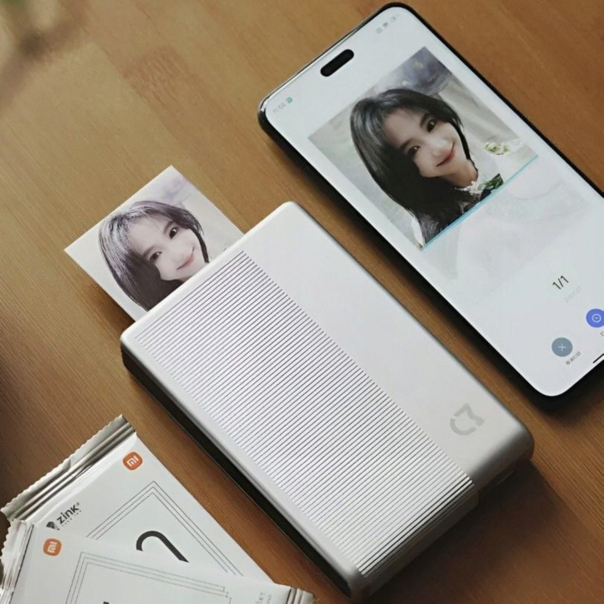 Una stampante fotografica argentata con una foto in uscita, accanto a uno smartphone.