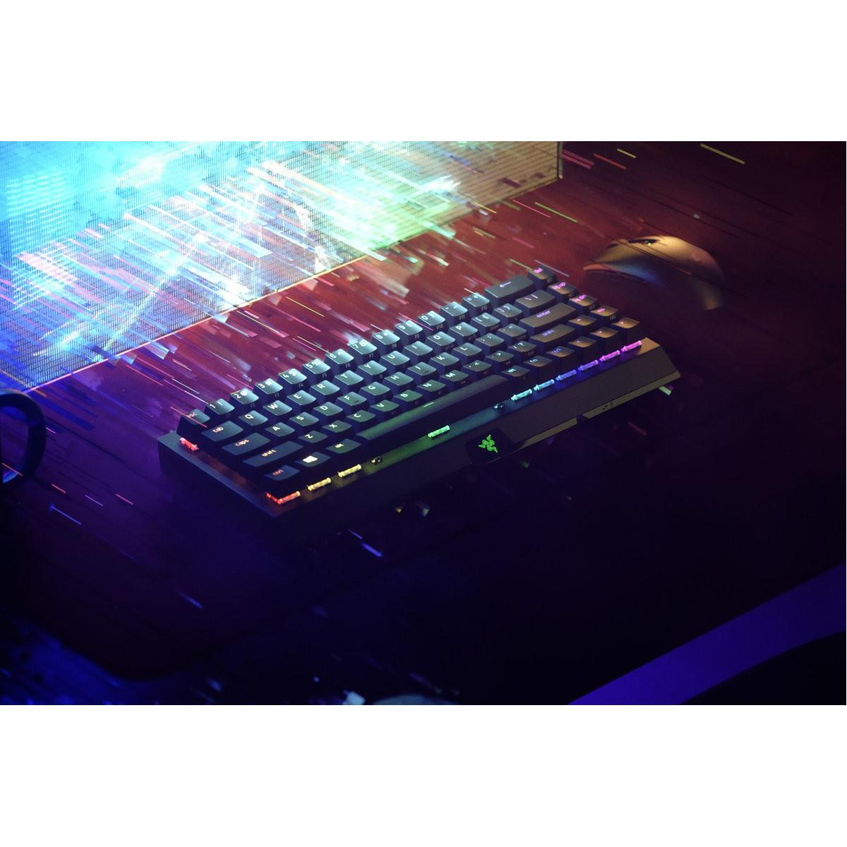 Eine schwarze Tastatur mit RGB-Beleuchtung steht auf einem dunklen Schreibtisch neben einer Maus.