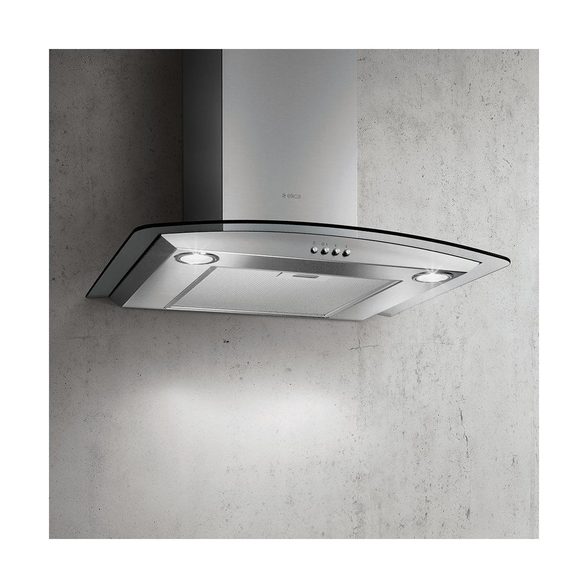 Una cappa aspirante moderna ed elegante in acciaio inox con rifiniture in vetro è montata su un muro di cemento grigio.