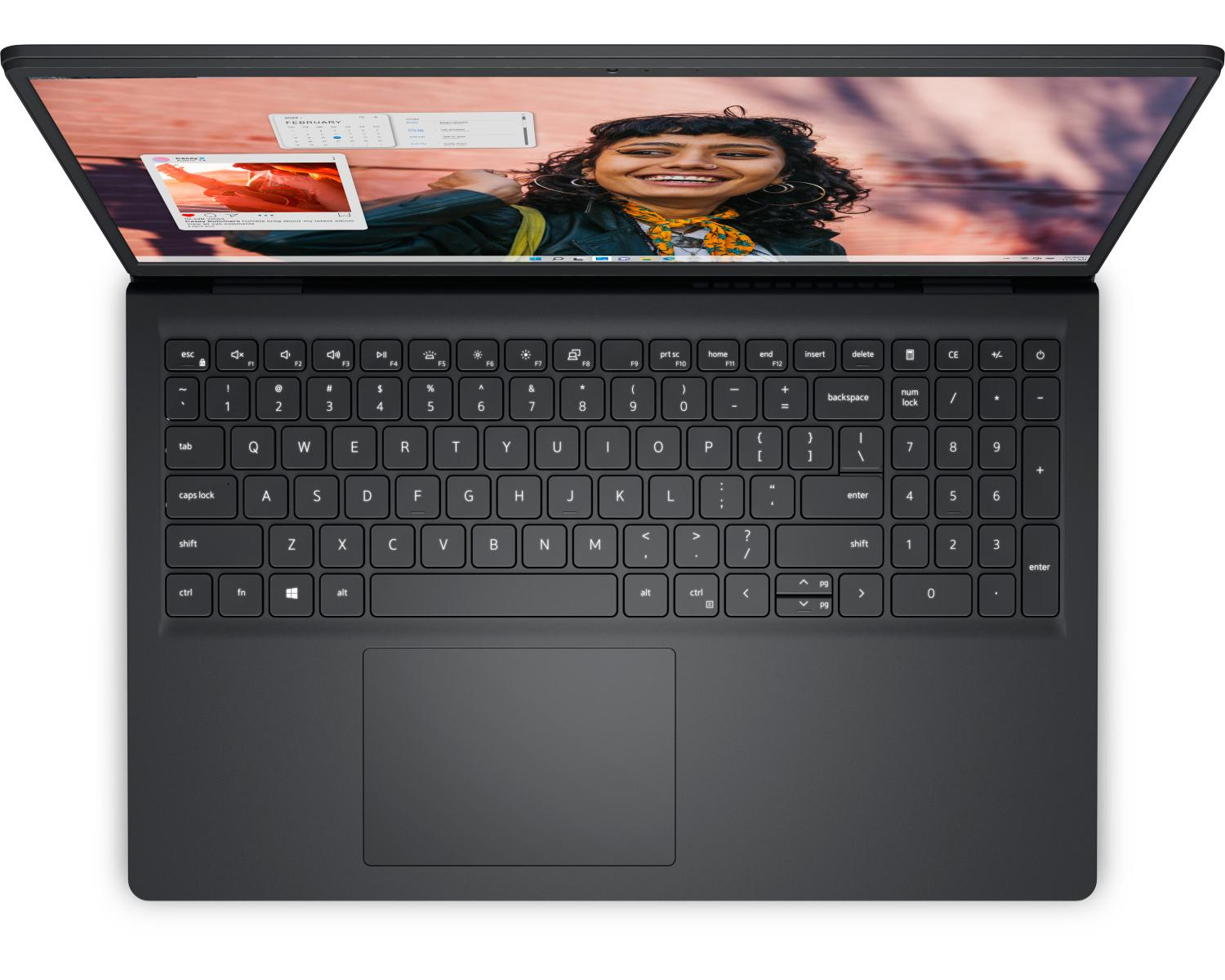 Un laptop nero è aperto, mostra una donna sorridente sul suo schermo. Tastiera visibile.