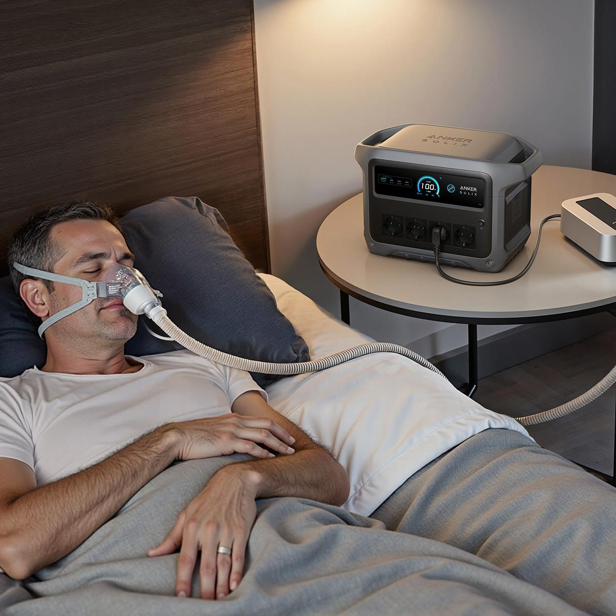 Bir adam yatakta, taşınabilir güç istasyonuna bağılı CPAP maskesiyle uyuyor.