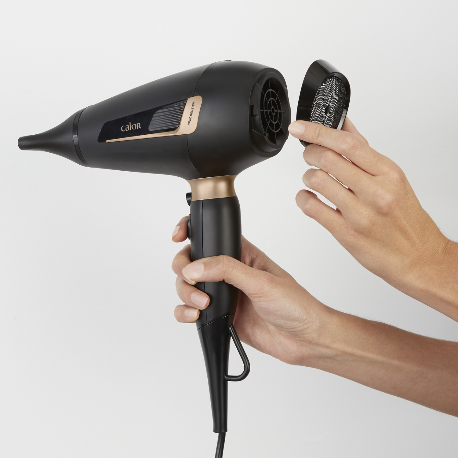 Een zwarte haardroger met gouden accenten wordt door handen vastgehouden.