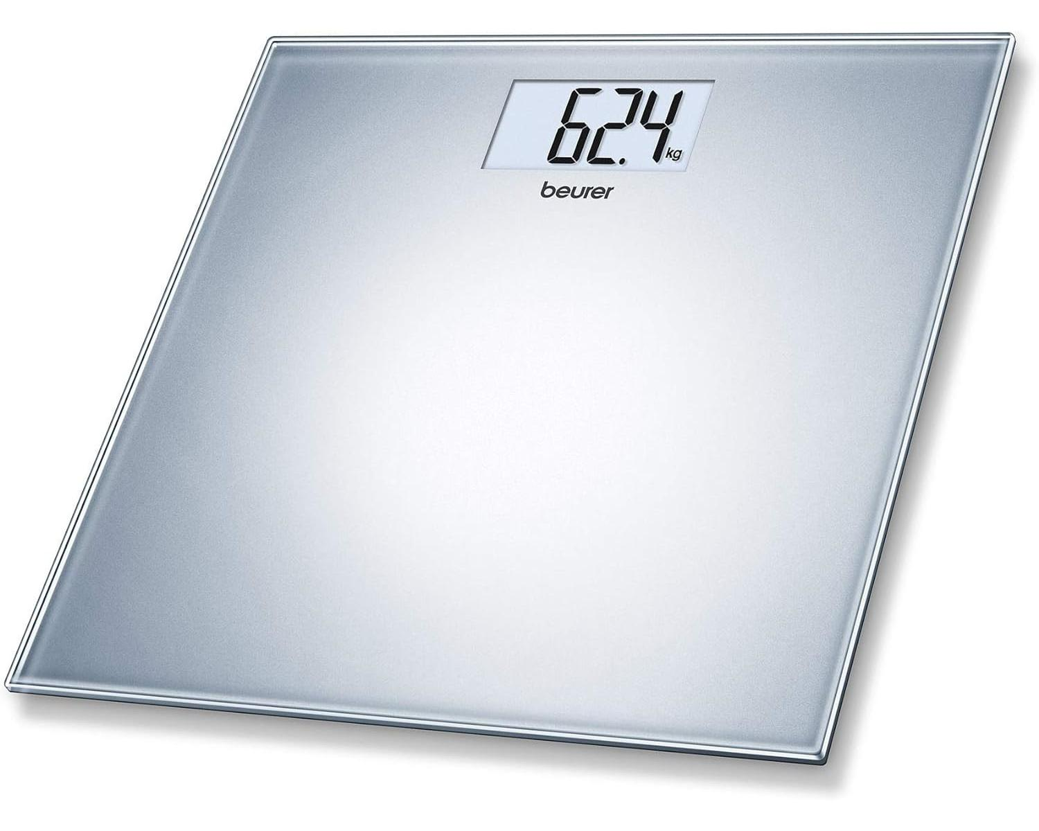Una bilancia digitale argentata mostra 62,4 kg. La bilancia ha una superficie in vetro e un display digitale.