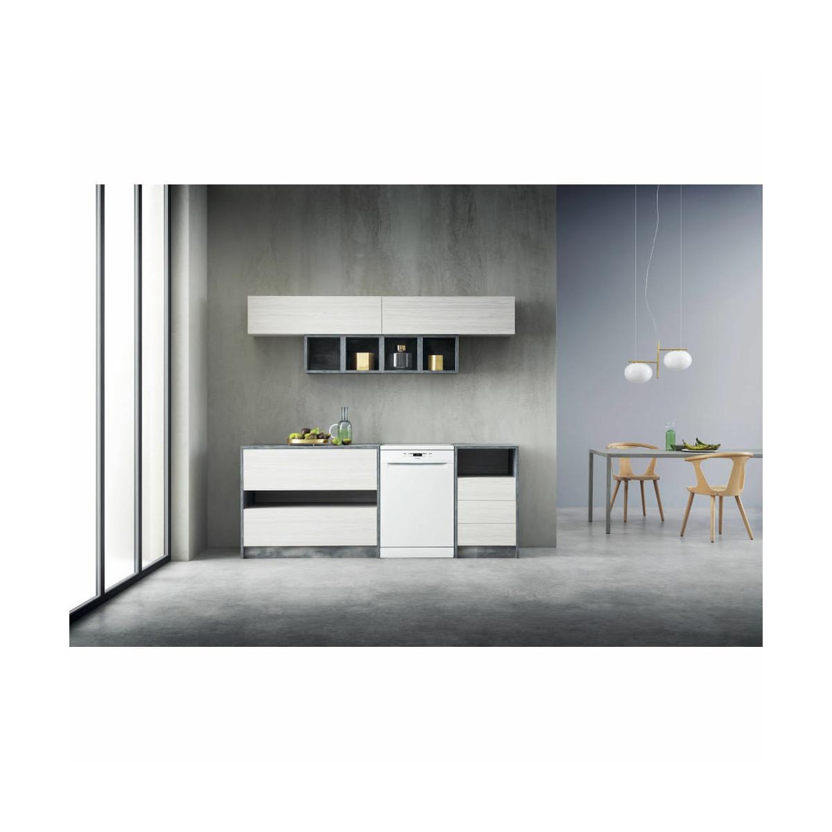 Cucina moderna con elettrodomestici bianchi, parete grigia e tavolo da pranzo.