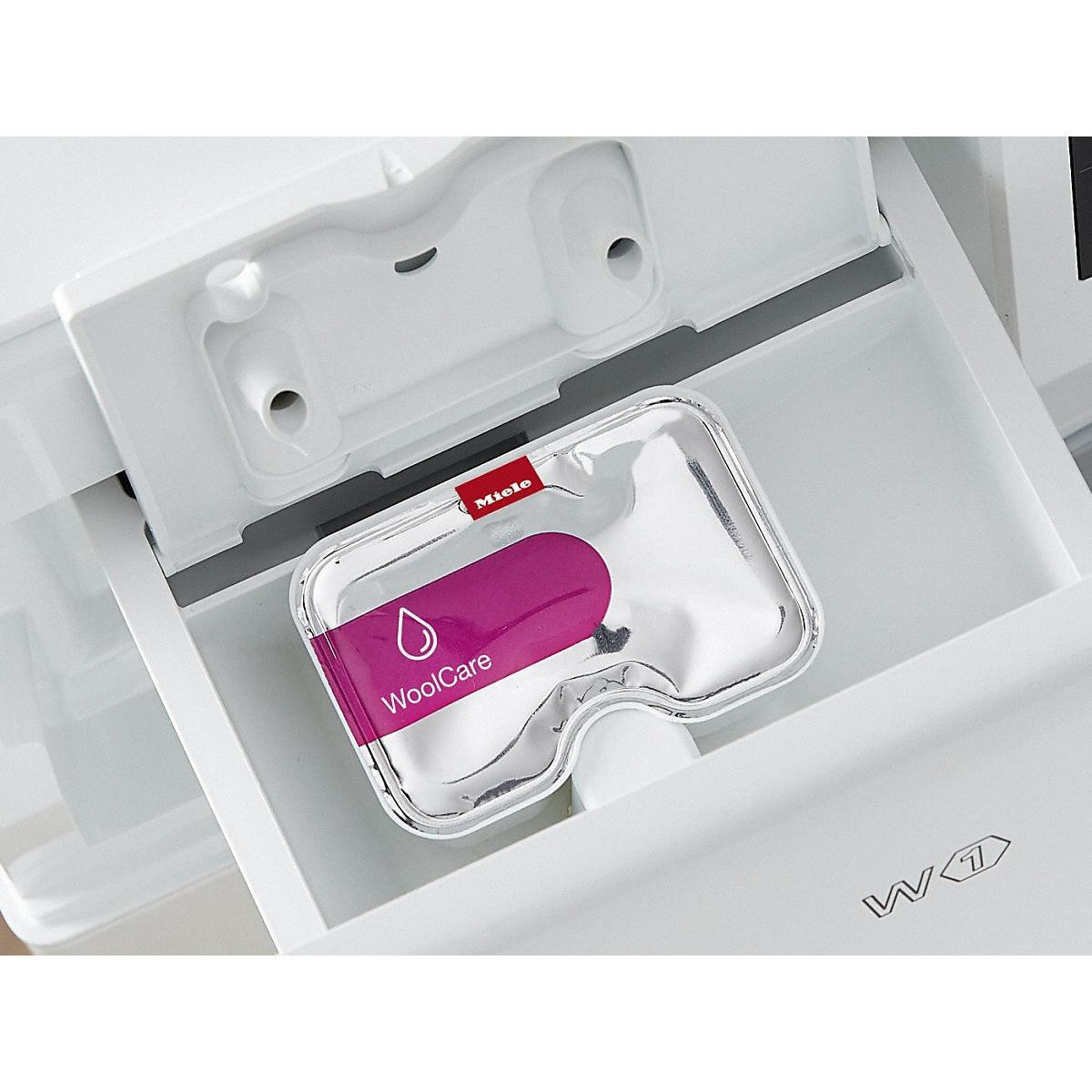 Una capsula di detersivo Miele WoolCare si trova in un cassetto bianco della lavatrice.