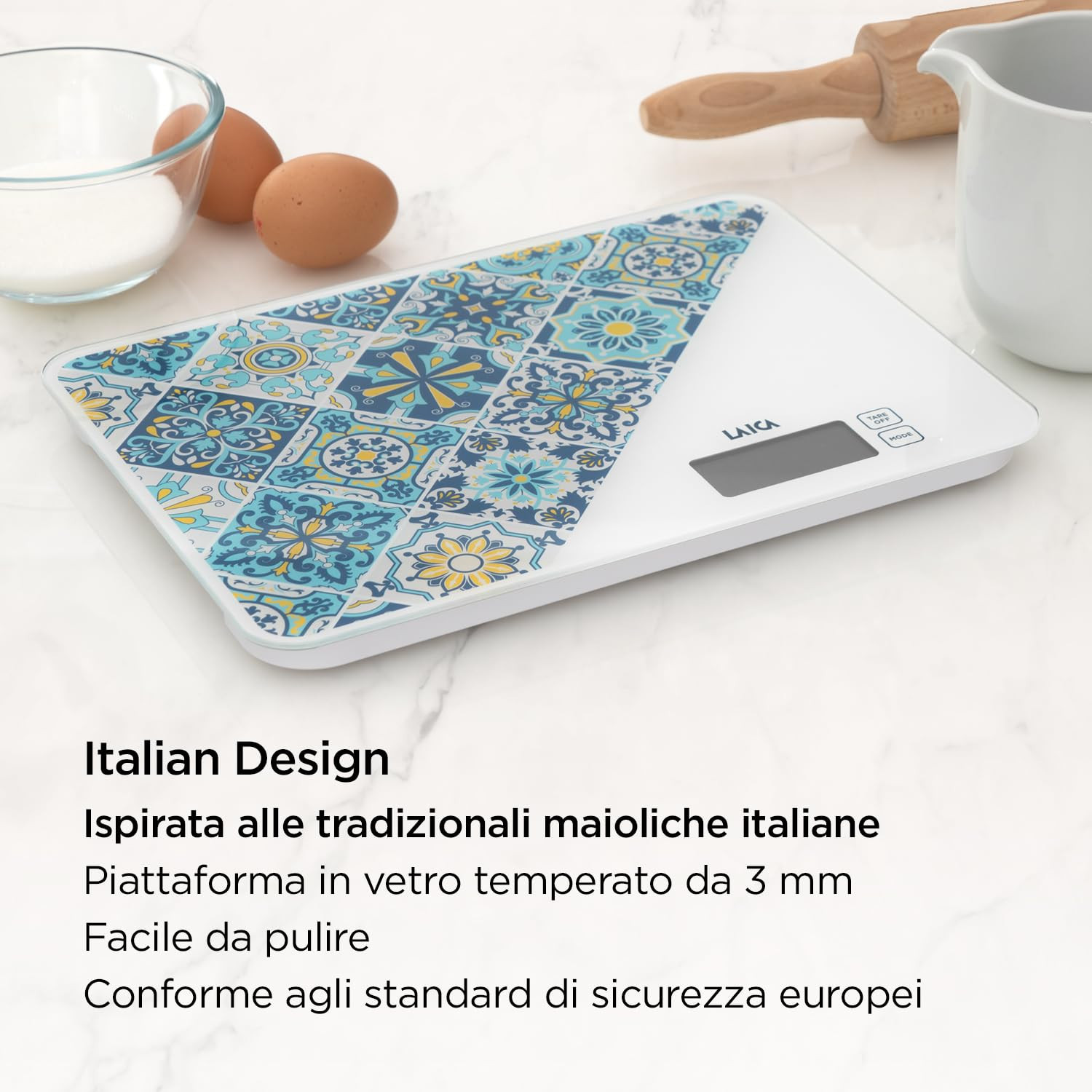 Eine weiße Küchenwaage mit italienischem Fliesenmuster, Eiern und Zuckerschale.