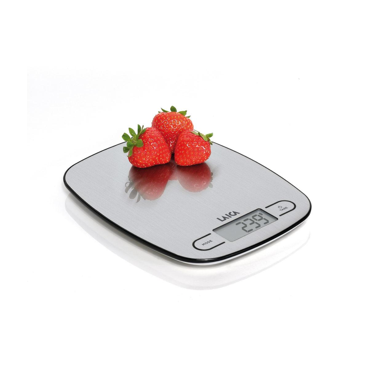 Three red strawberries rest on a silver digital kitchen scale showing 239.