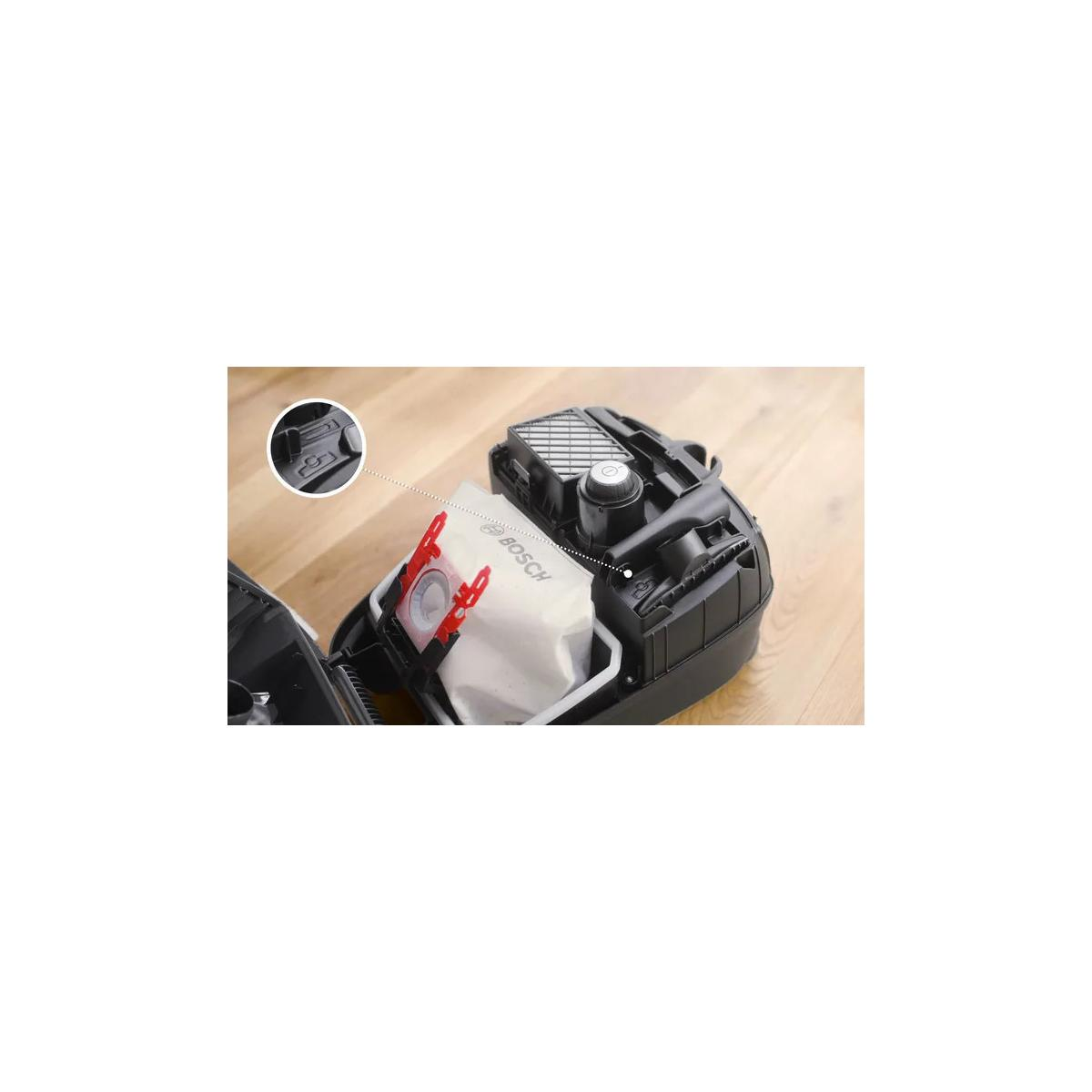 A black Bosch vacuum cleaner with a white dust bag and red holder.