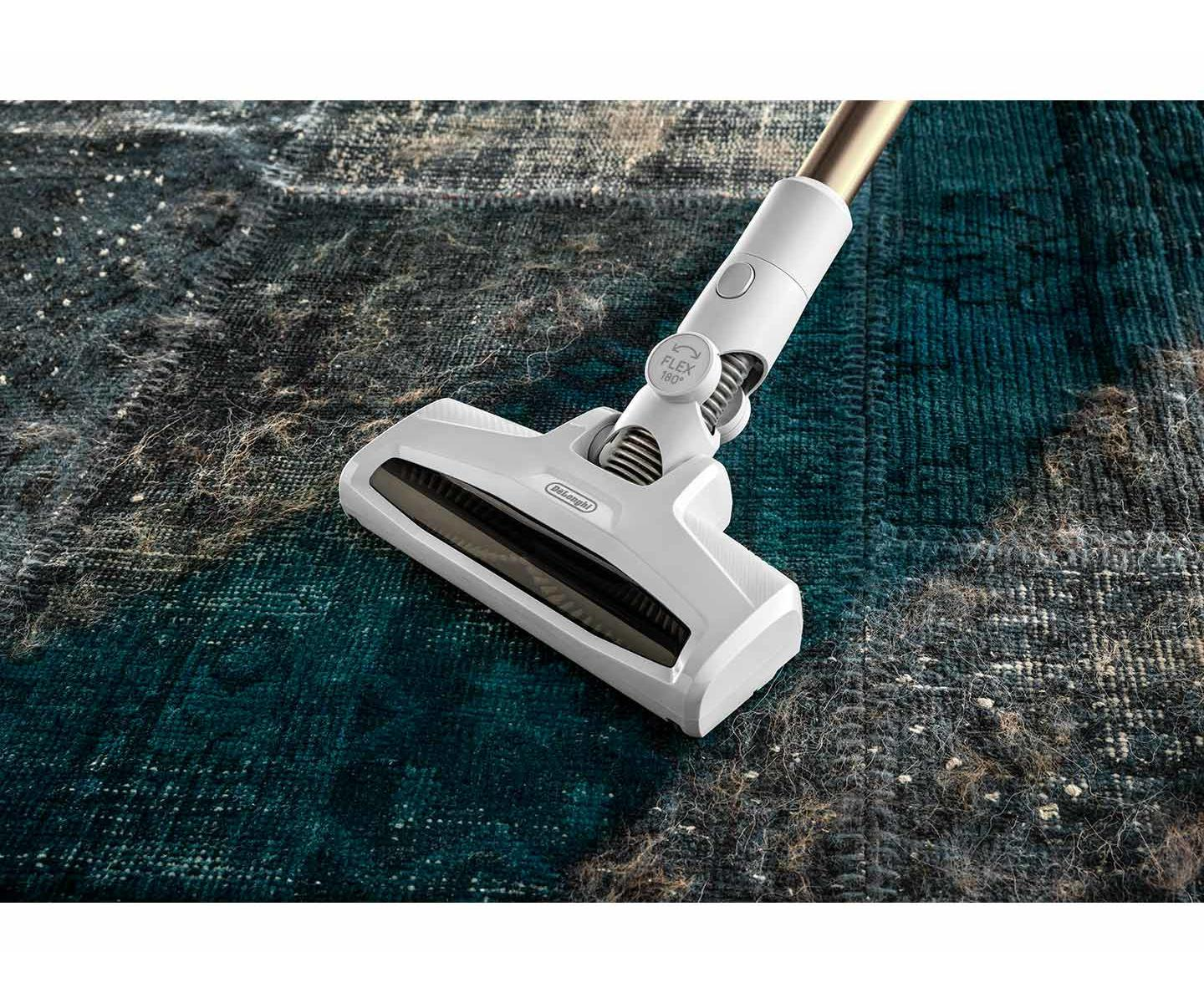 Una testina aspirapolvere bianca pulisce un tappeto blu e grigio con detriti.