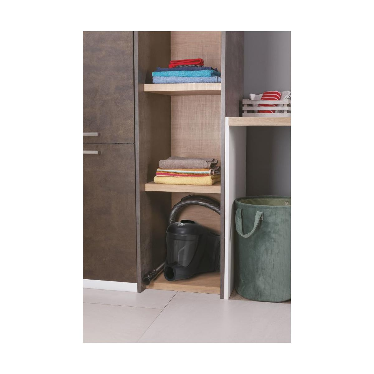 A black vacuum cleaner with hose sits on a shelf near folded towels and a green laundry basket.
