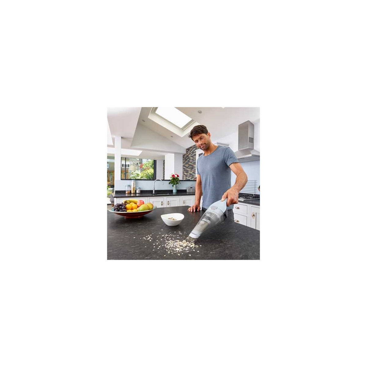 Un homme passe l'aspirateur sur le plan de travail de la cuisine.