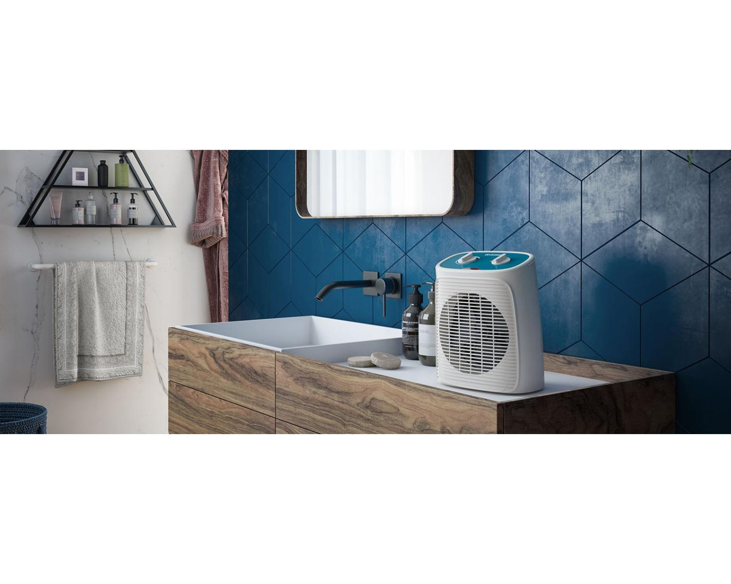 Un calefactor portátil blanco sobre un mueble de baño de madera con lavabo y espejo.