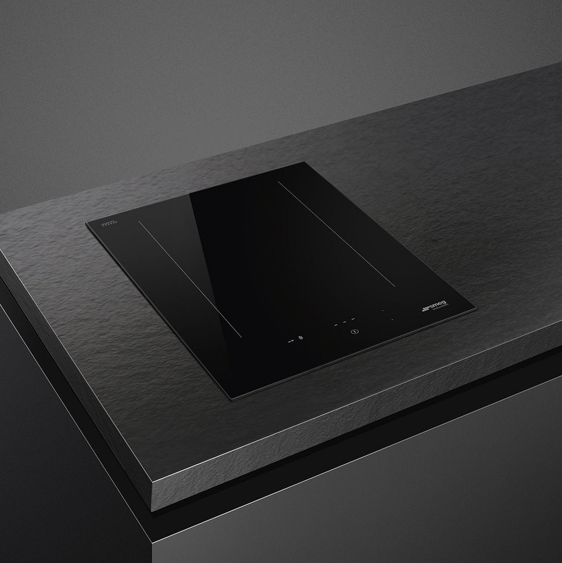 Piano cottura a induzione nero con comandi touch su piano di lavoro scuro.