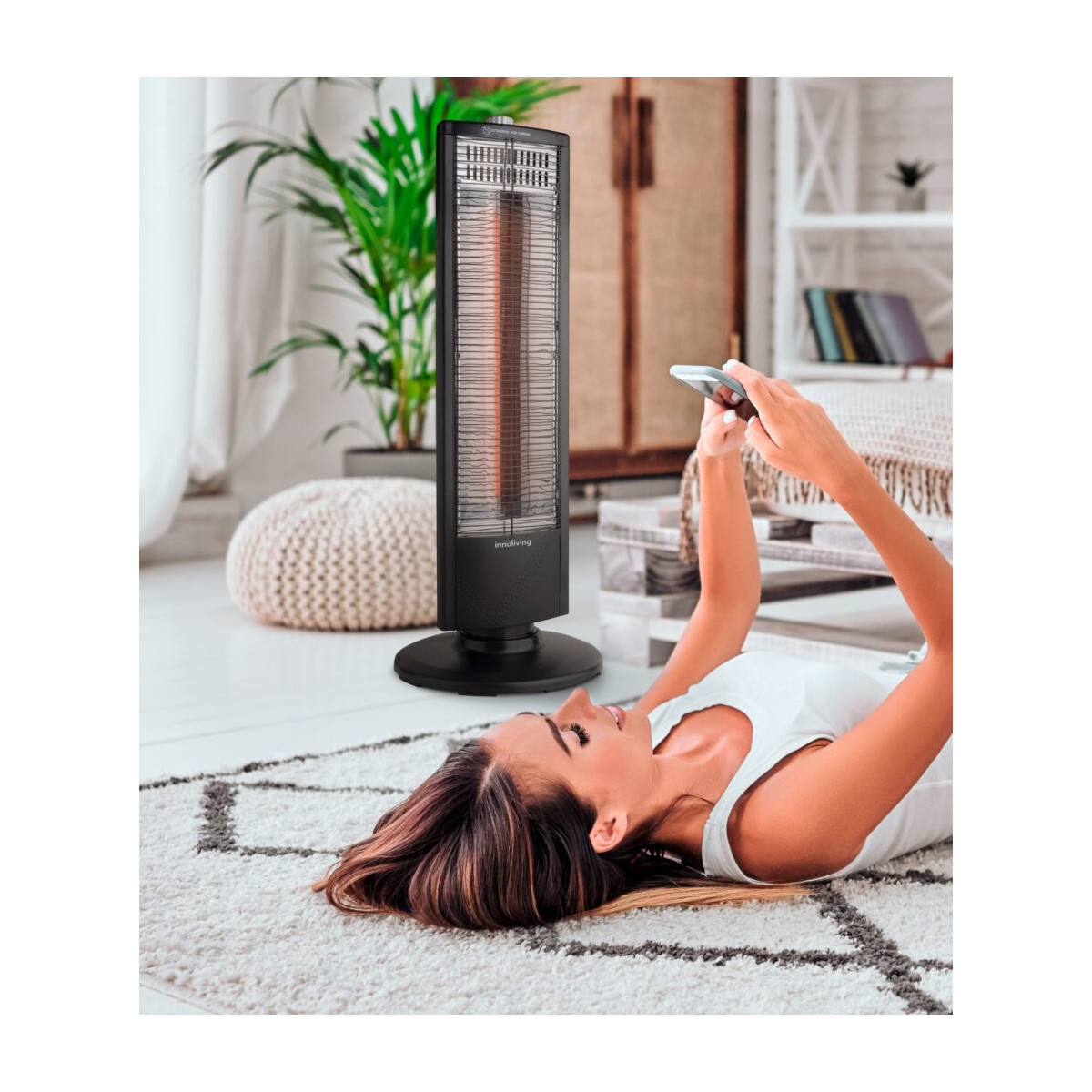Una donna è sdraiata su un tappeto usando il telefono, con un termosifone in piedi accanto.