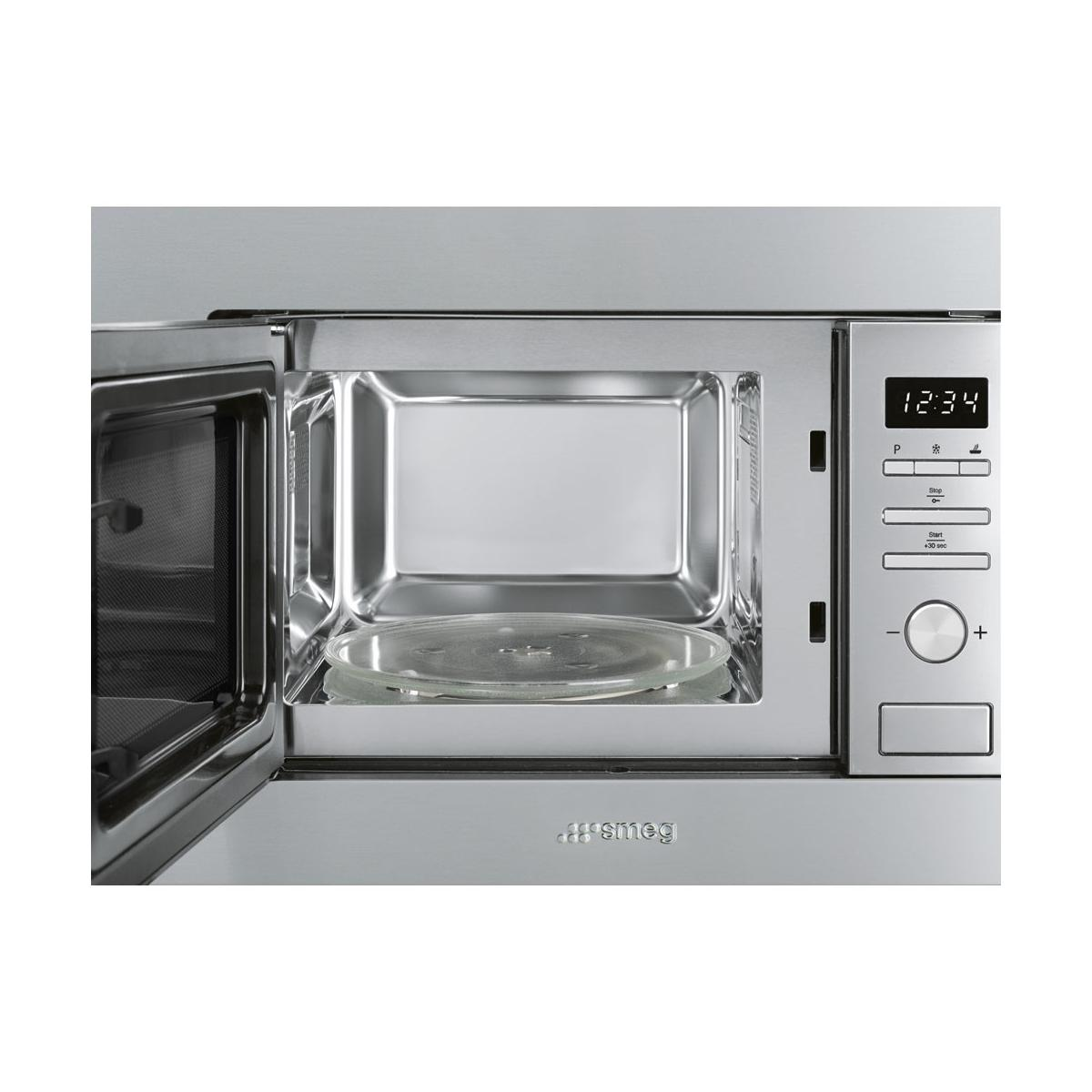 Un four à micro-ondes Smeg argenté, porte ouverte, avec plateau en verre.