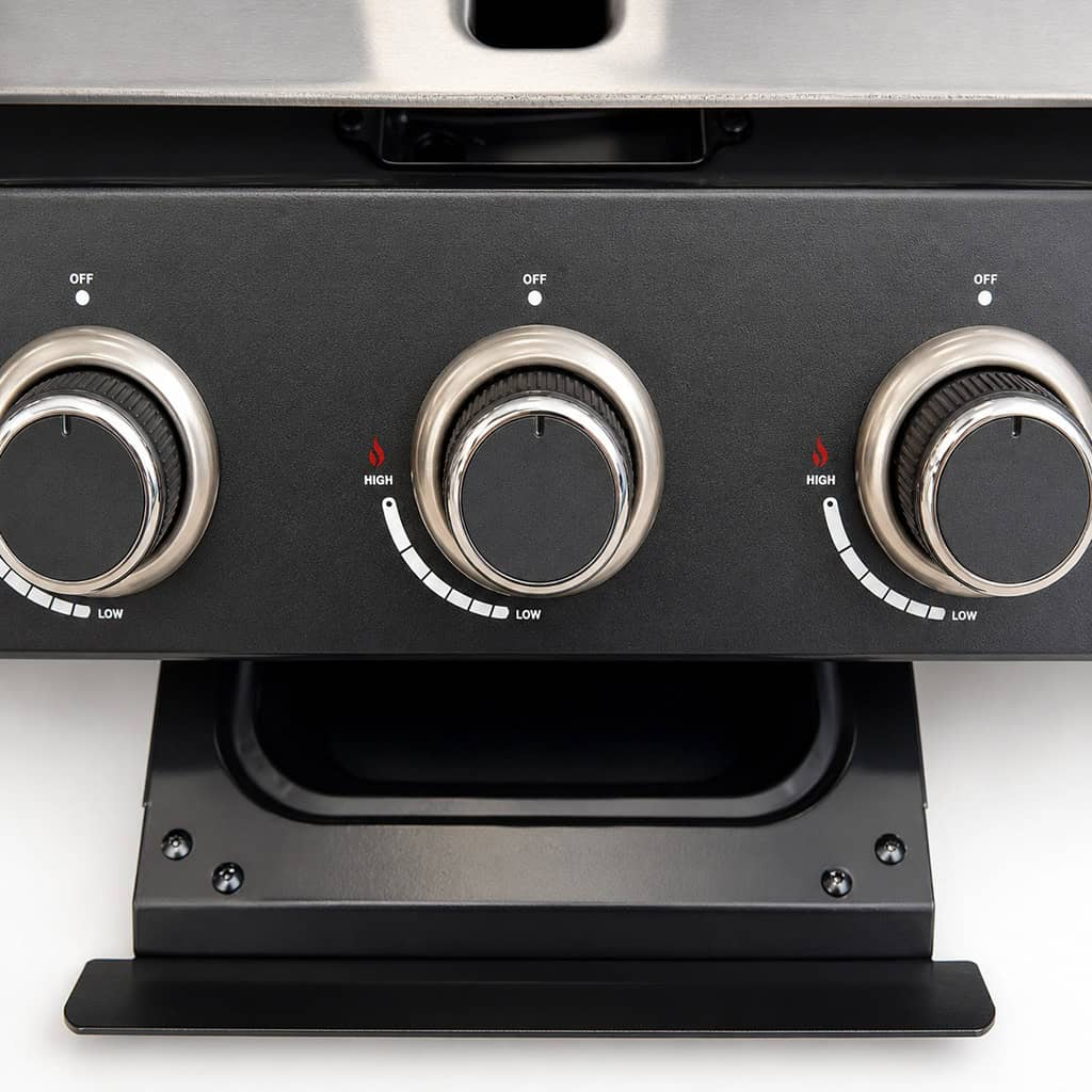 Close-up van drie zwarte bedieningsknoppen met metalen rand, gemonteerd op een grill.