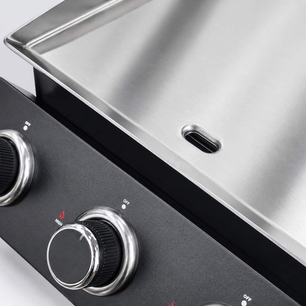 Close-up van een grill met zilveren knoppen en een zwart voorpaneel.