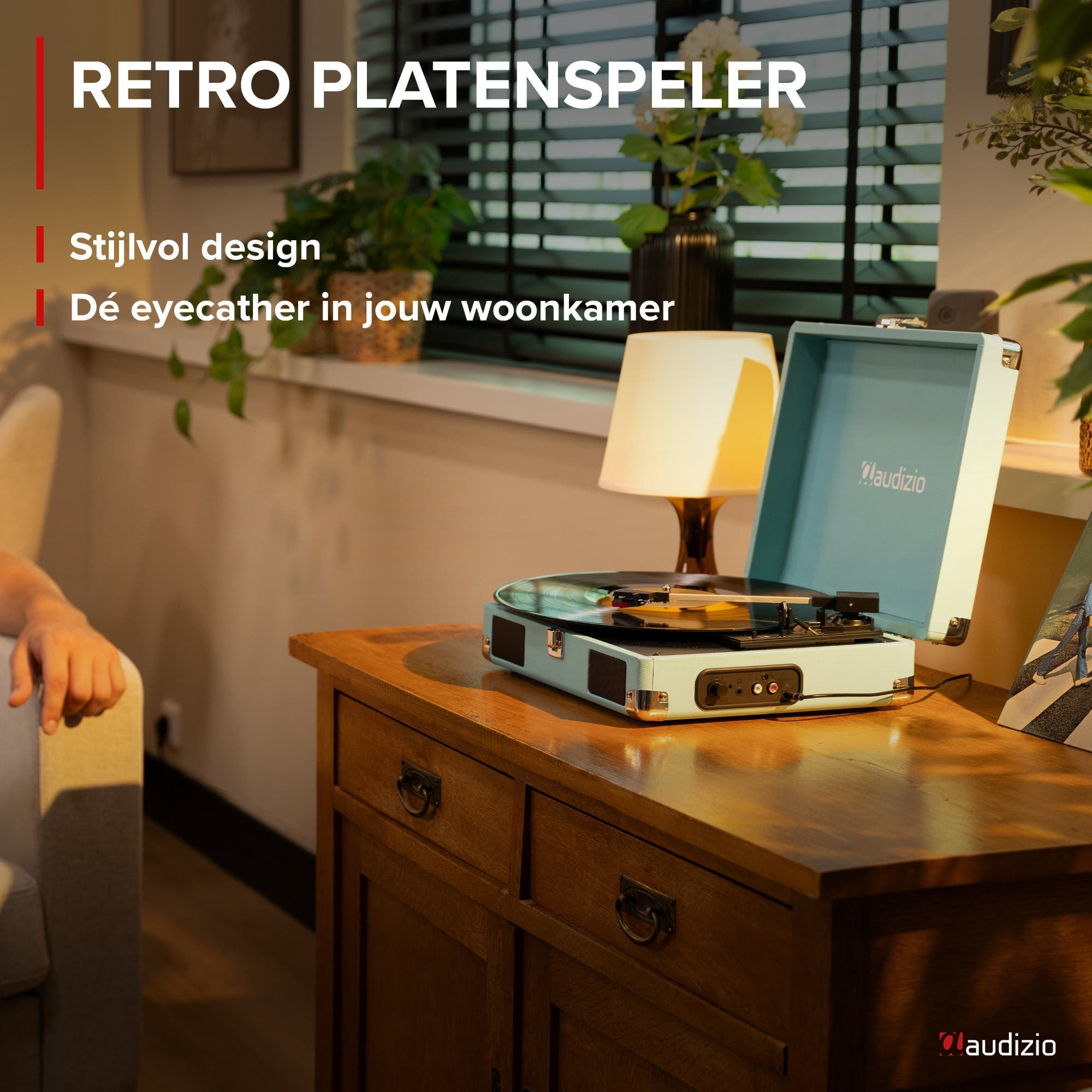 Un tocadiscos azul claro sobre una mesa de madera, con lámpara y plantas.