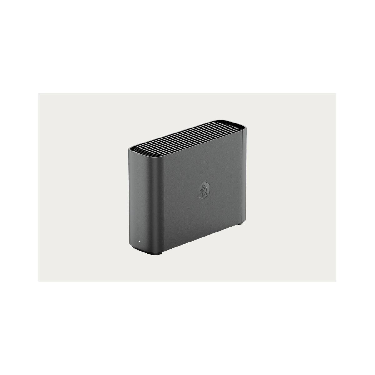Un disco duro externo gris oscuro con parte superior acanalada sobre fondo liso.