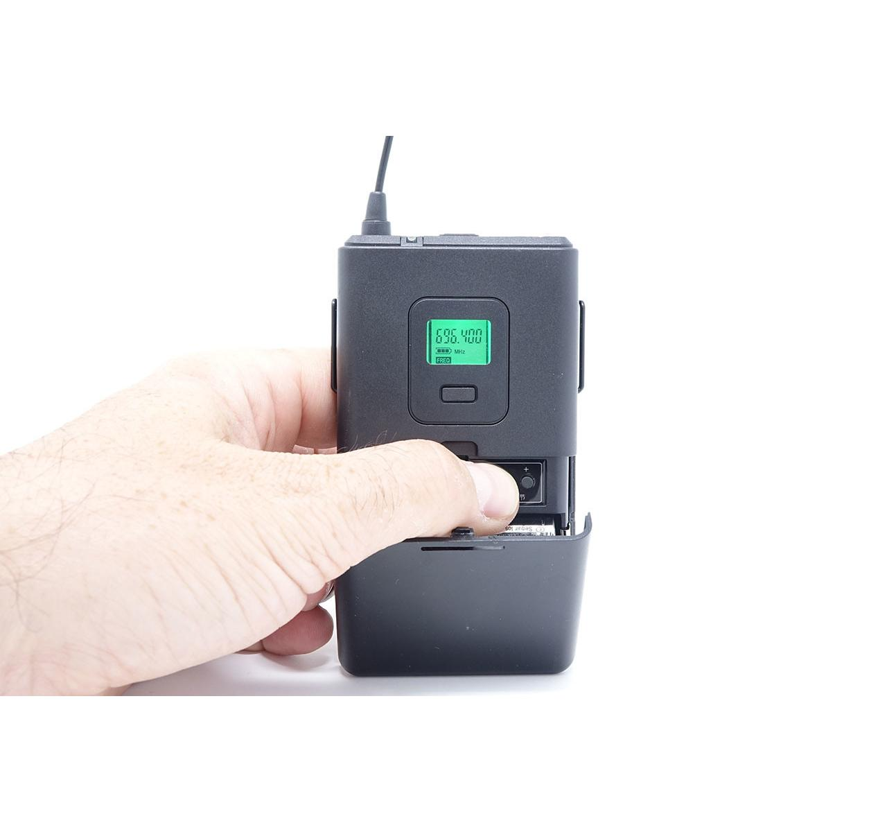 Eine Hand öffnet ein schwarzes Elektronikgerät mit grünem Bildschirm.