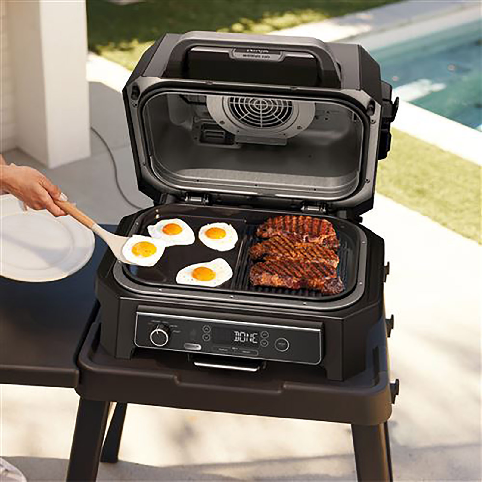 A grill with steaks and fried eggs, with a pool nearby.