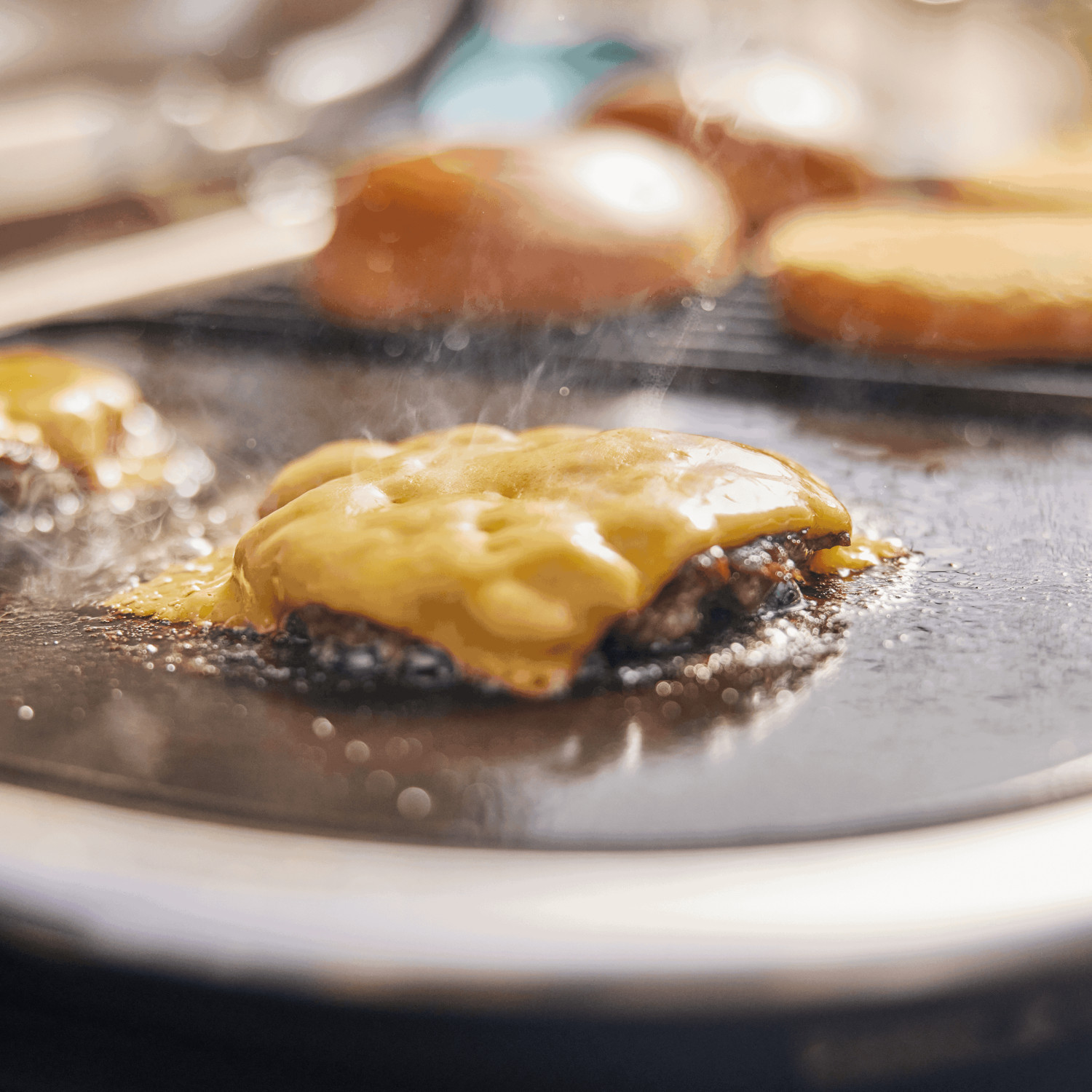 Kotlet burgera z roztopionym serem jest smażony na grillu.