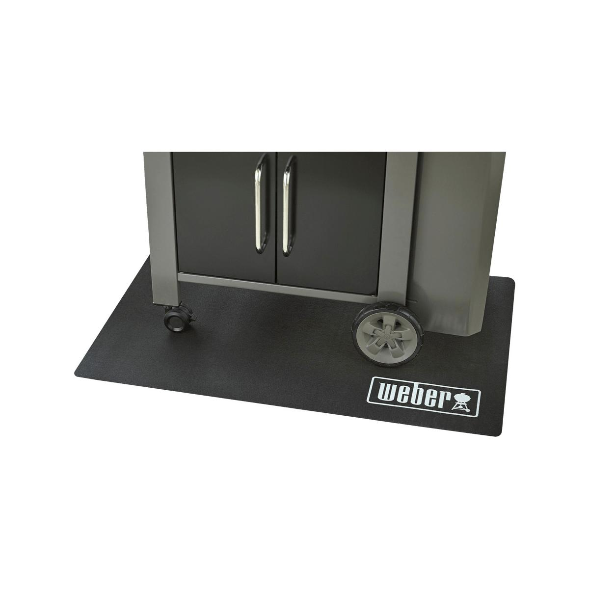 Ein Weber Grill auf einer schwarzen Matte, mit zwei Rädern und silbernen Griffen.